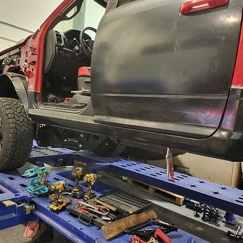 A red and black truck is sitting on top of a blue table in a garage.