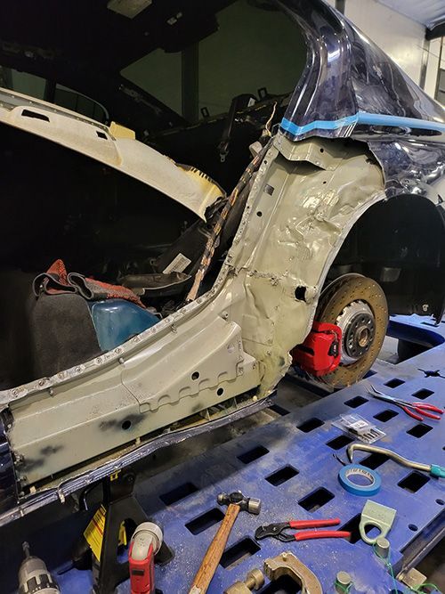 A car is being repaired in a garage with tools.