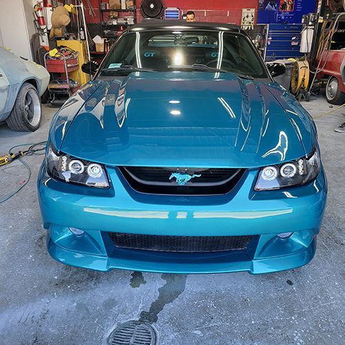 A blue mustang is parked in a garage.