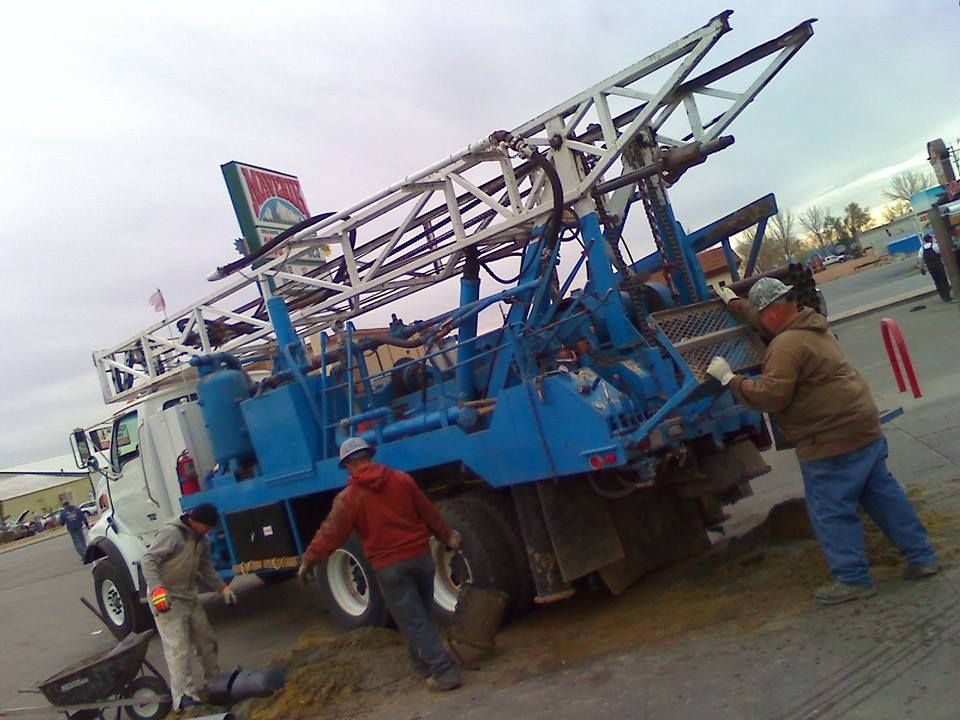Two men are standing next to a large blue truck