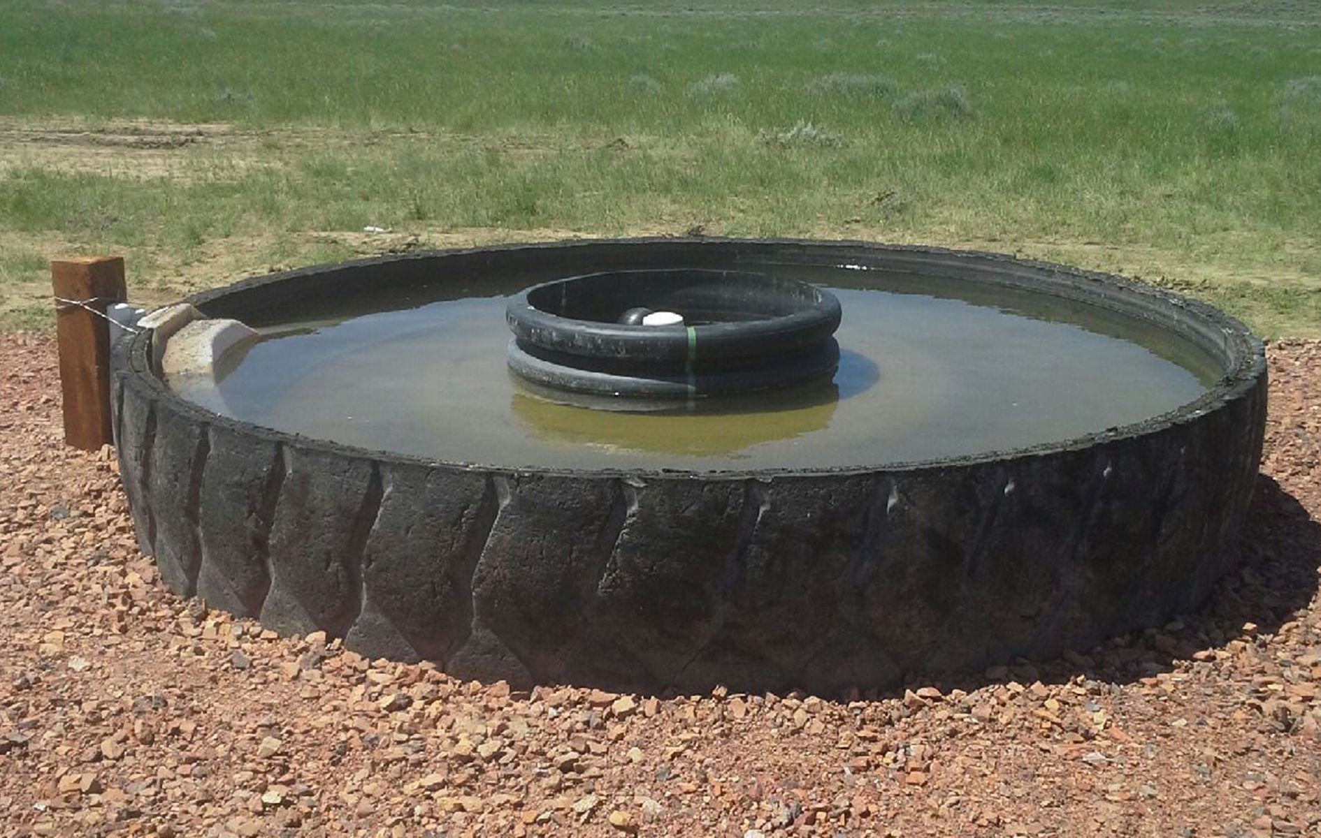 A large tire filled with water sits in the dirt