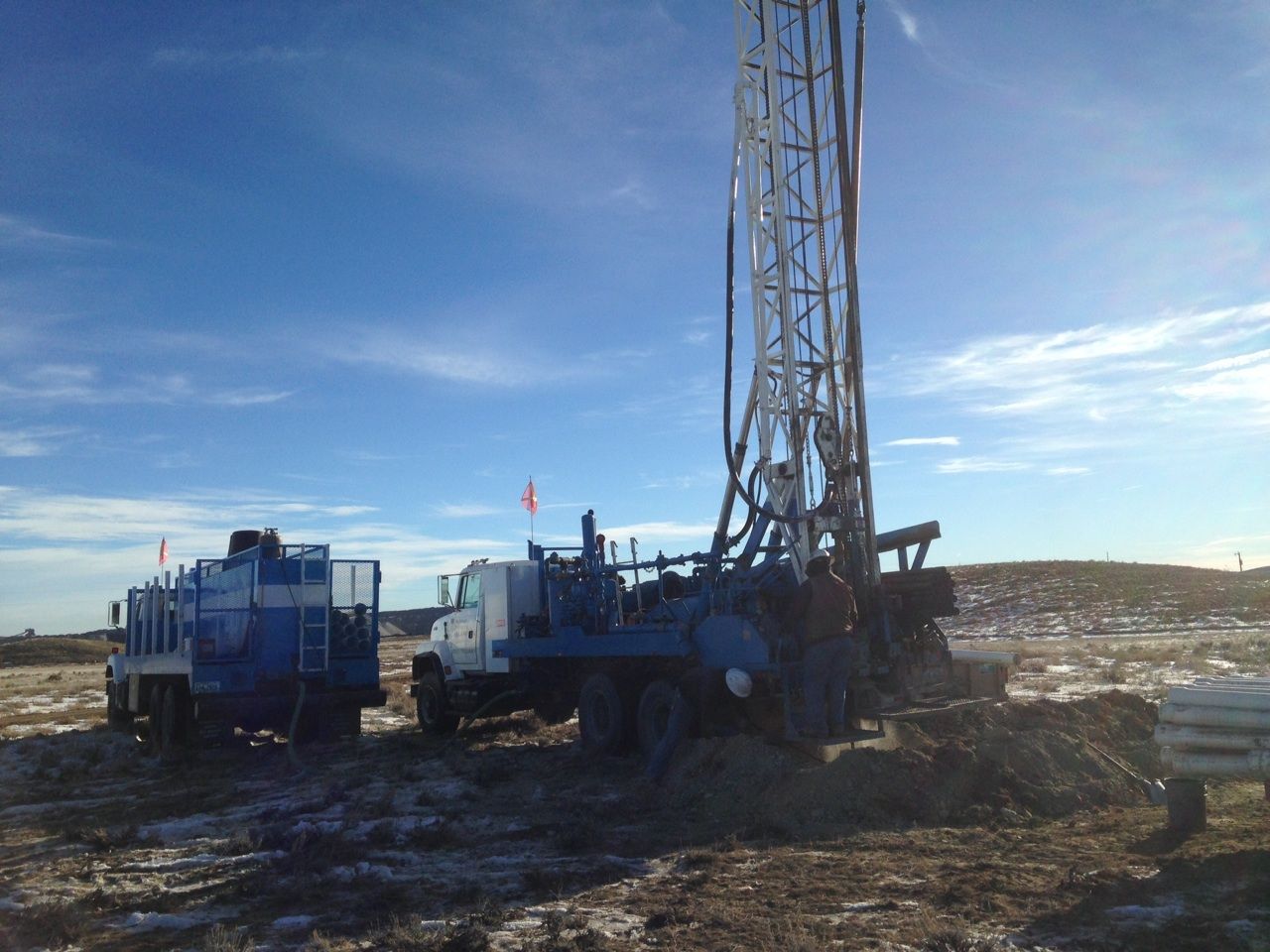 A truck is parked next to a drilling rig in a field.