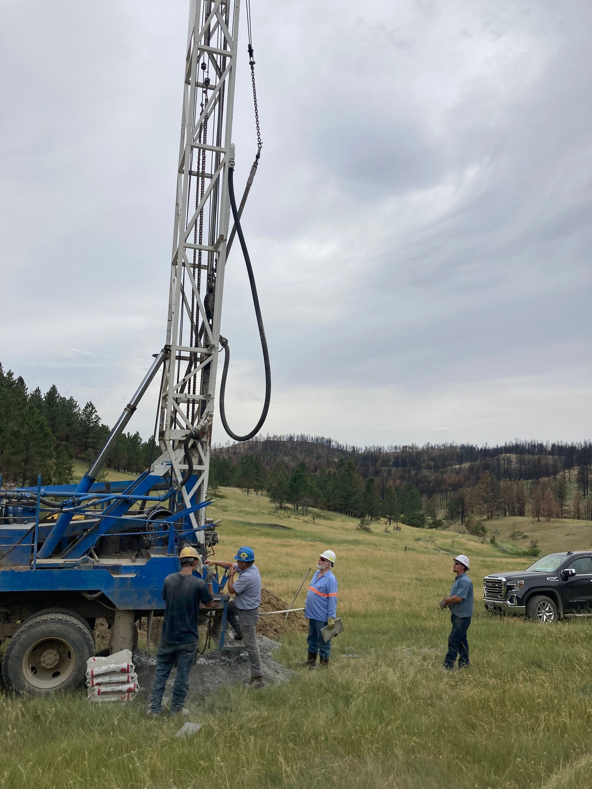 A group of men are standing in a grassy field in front of a large crane.