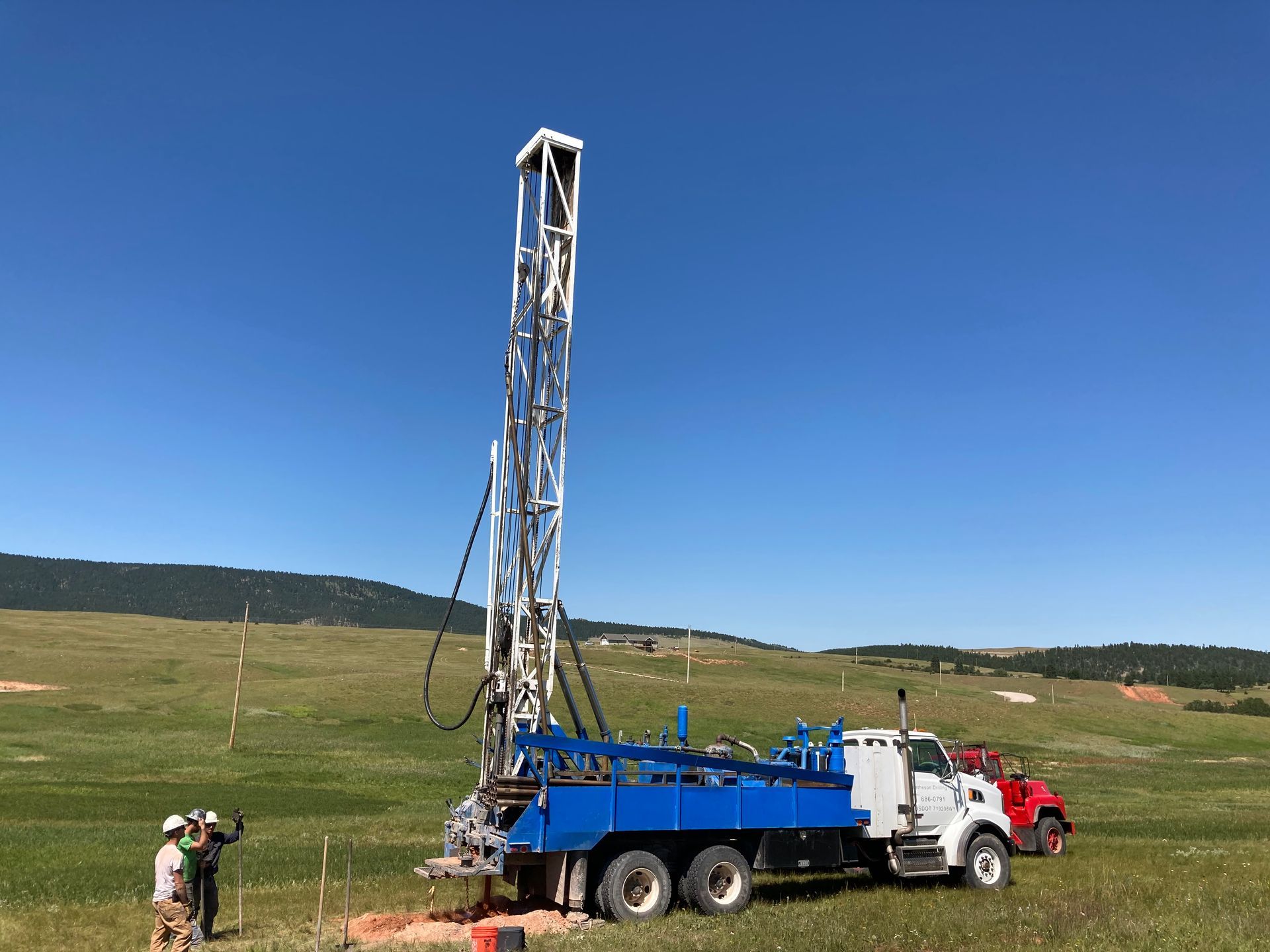 A blue truck is parked in a grassy field next to a red truck.