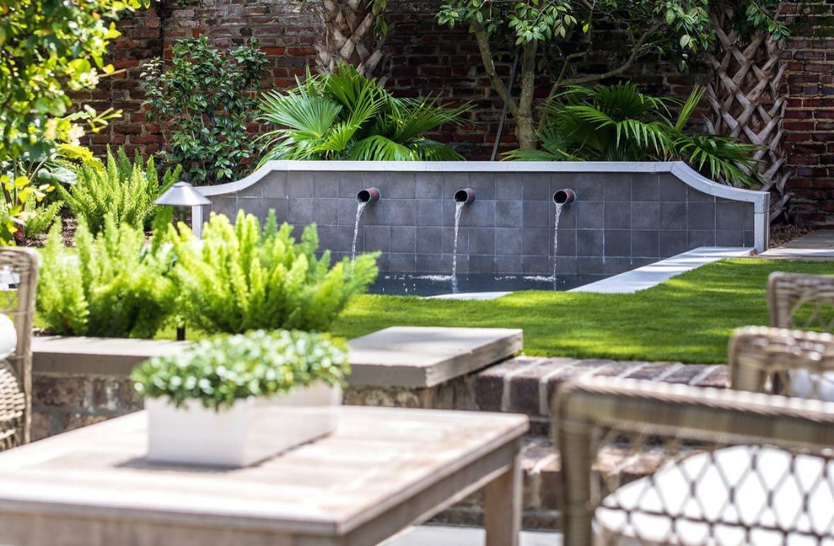 Modern garden patio with a dark stone water feature, potted plants, and outdoor seating