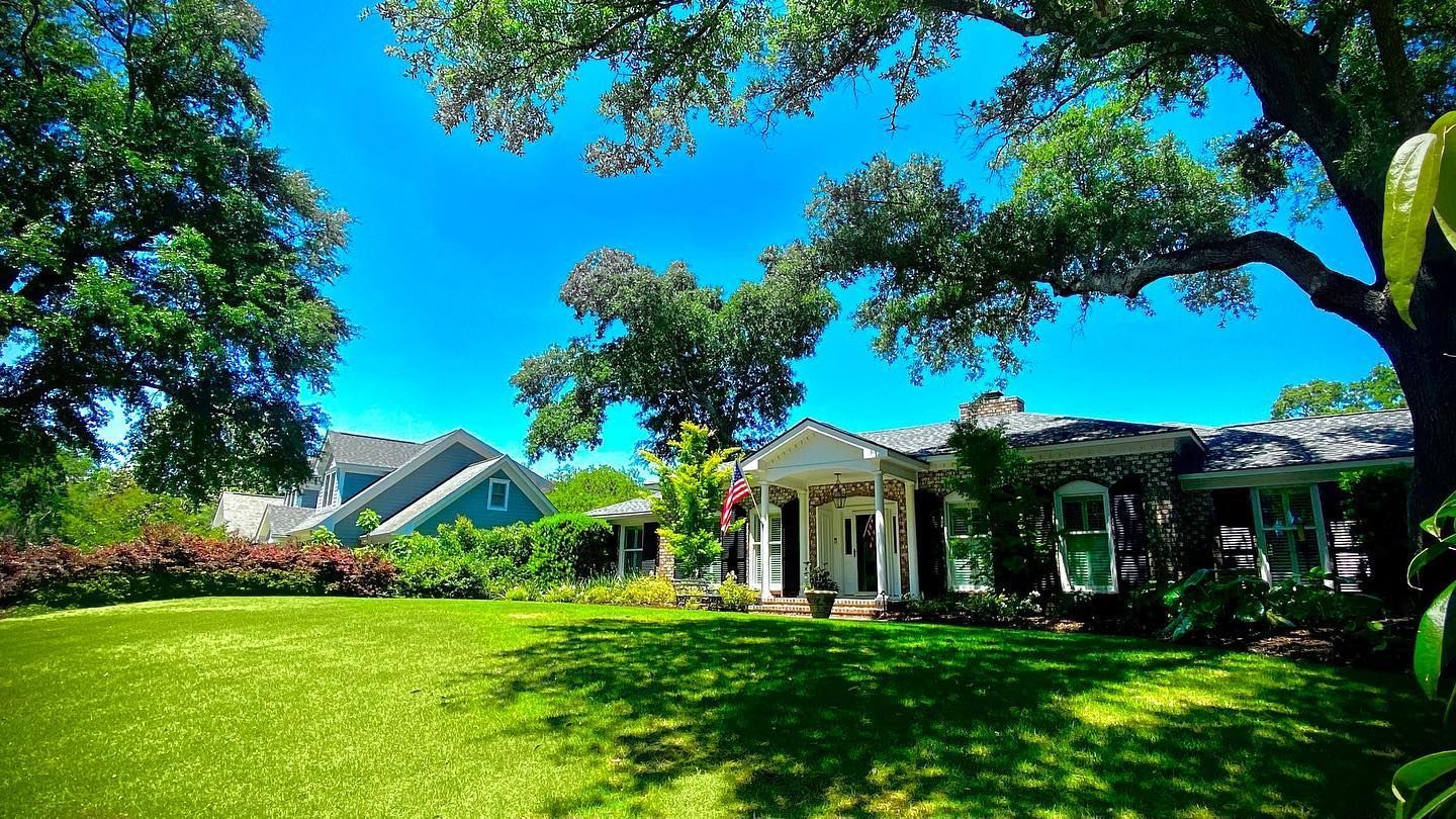Bright green lawn with a house, trees, and clear blue sky on a sunny day