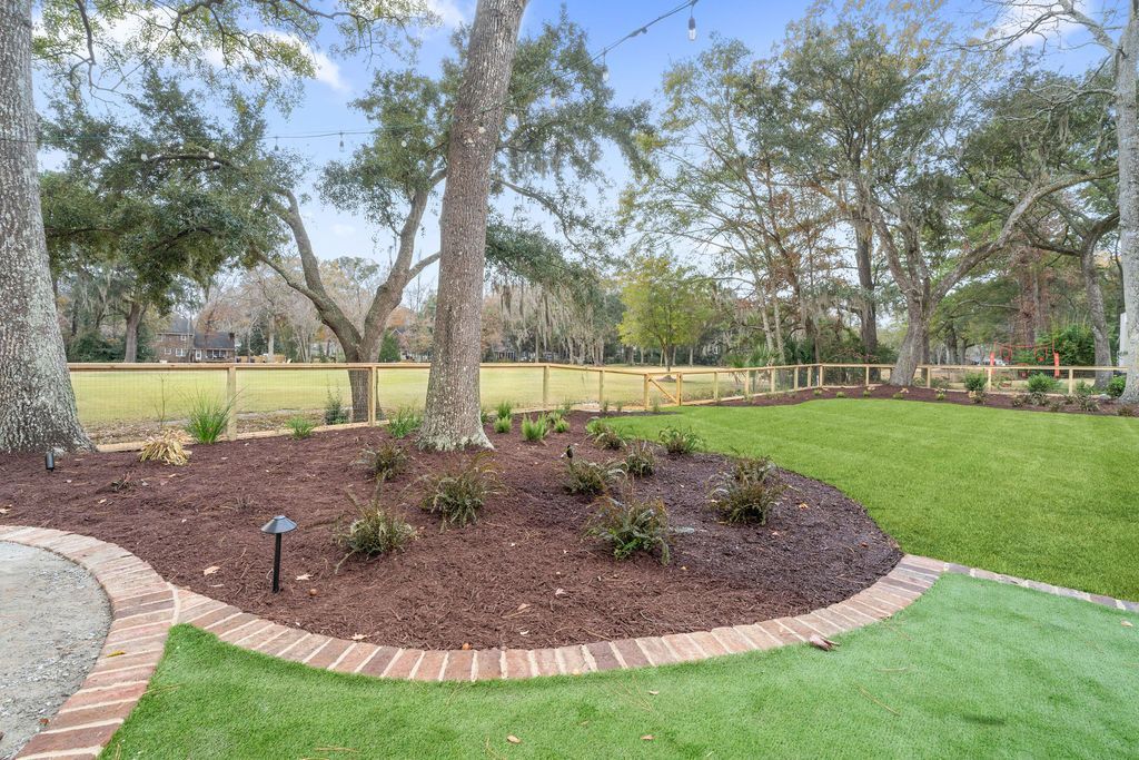 Landscaped garden bed with mulch, trees, and green lawn in a park-like setting