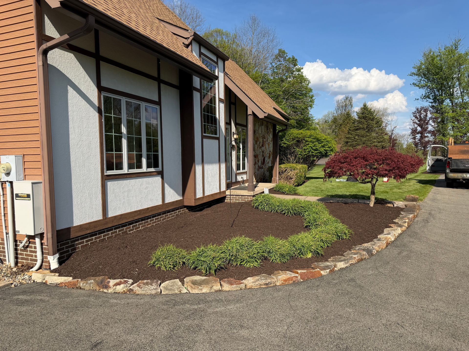 Front entrance of a house with landscaped flower beds beside a gravel driveway