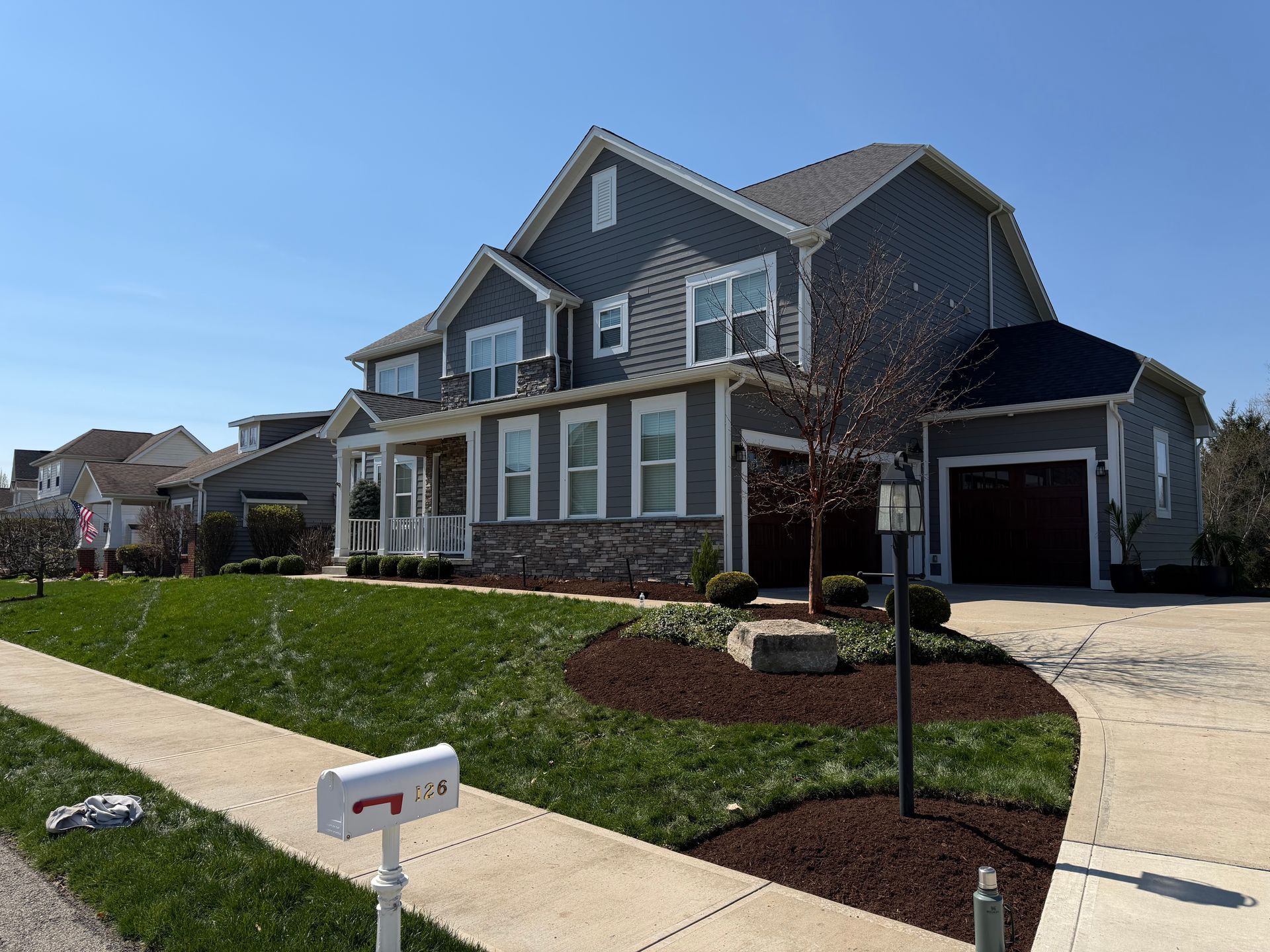 Suburban two-story blue house with white trim, front lawn, sidewalk, and attached garage