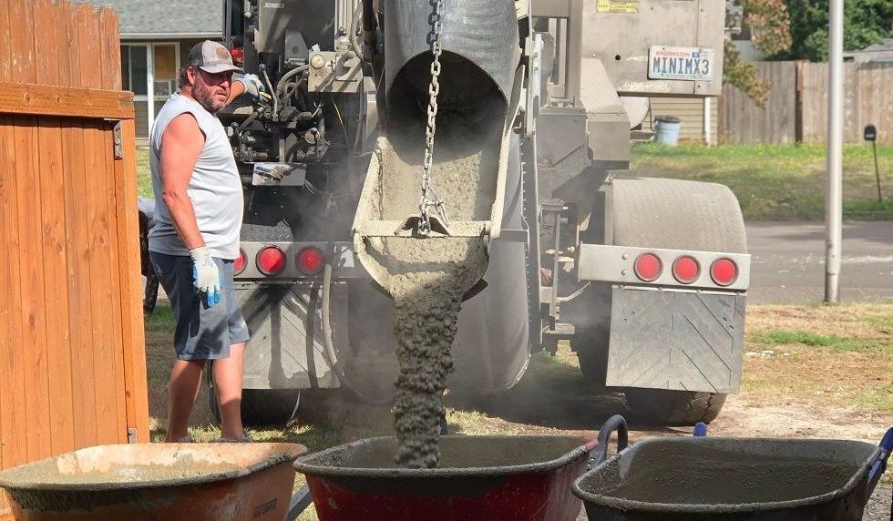 A man is pouring concrete into a wheelbarrow.
