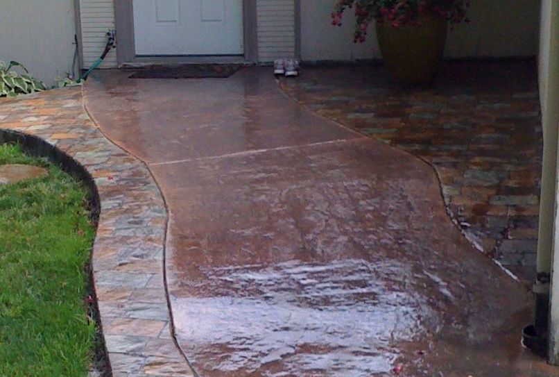A concrete walkway leading to the front door of a house.