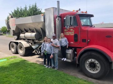 A family is standing in front of a red semi truck.