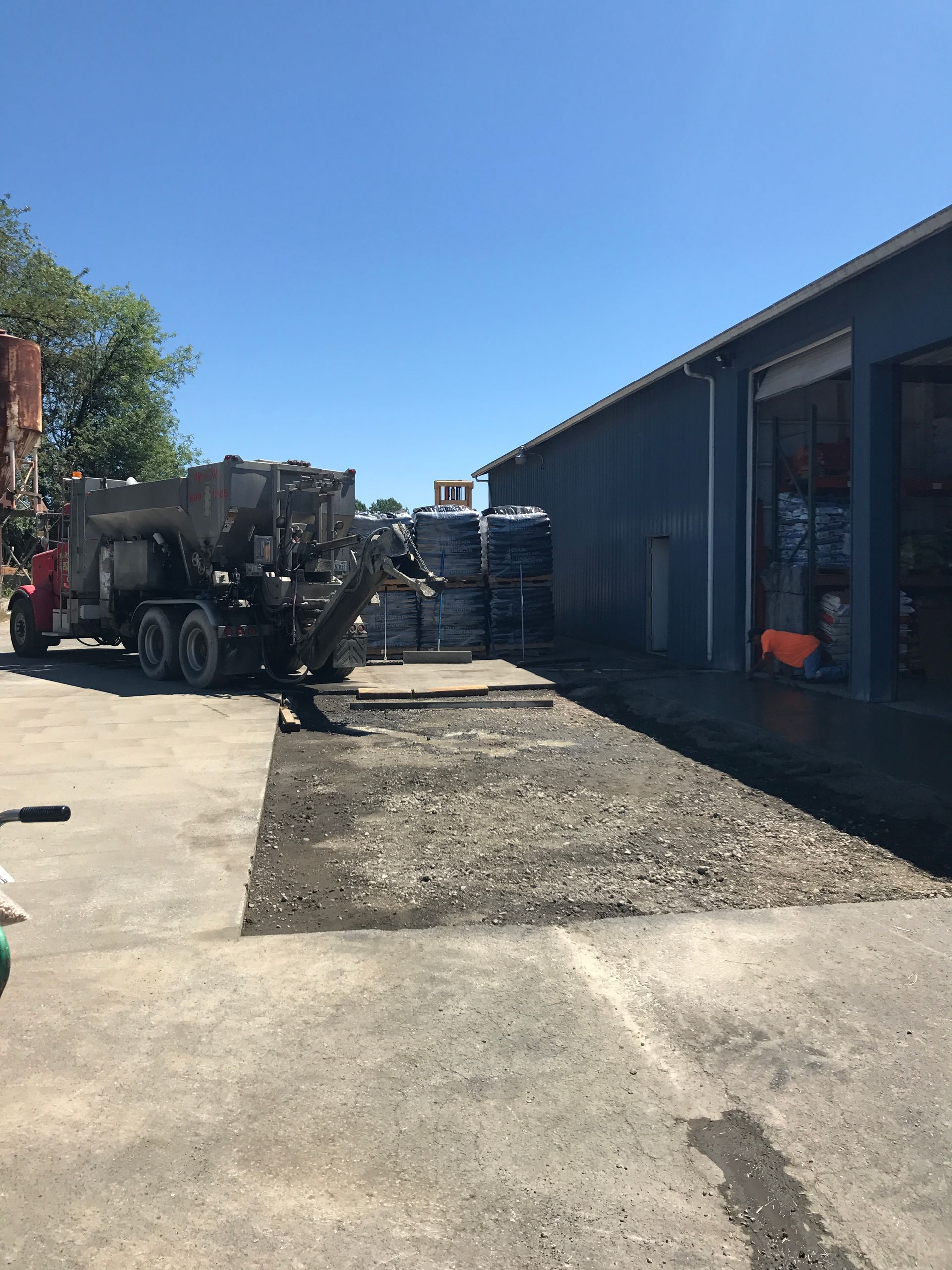 A truck is being loaded with concrete in front of a building.