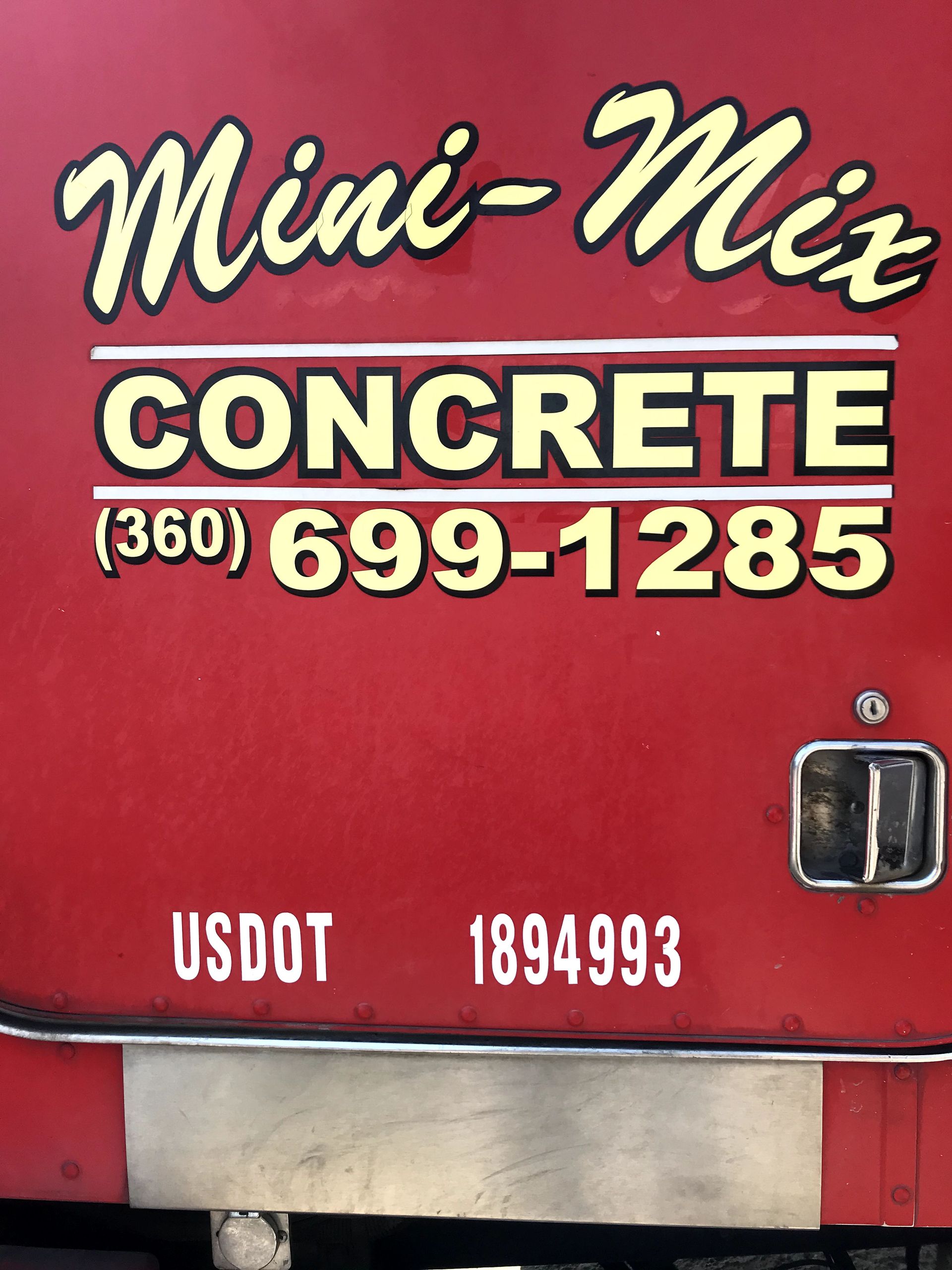A red mini-mix concrete truck is parked