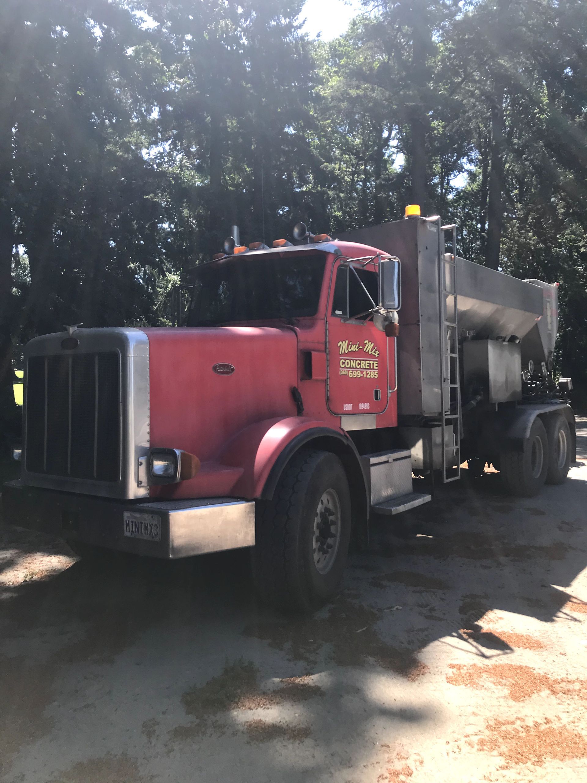 A red truck is parked in a parking lot with trees in the background.