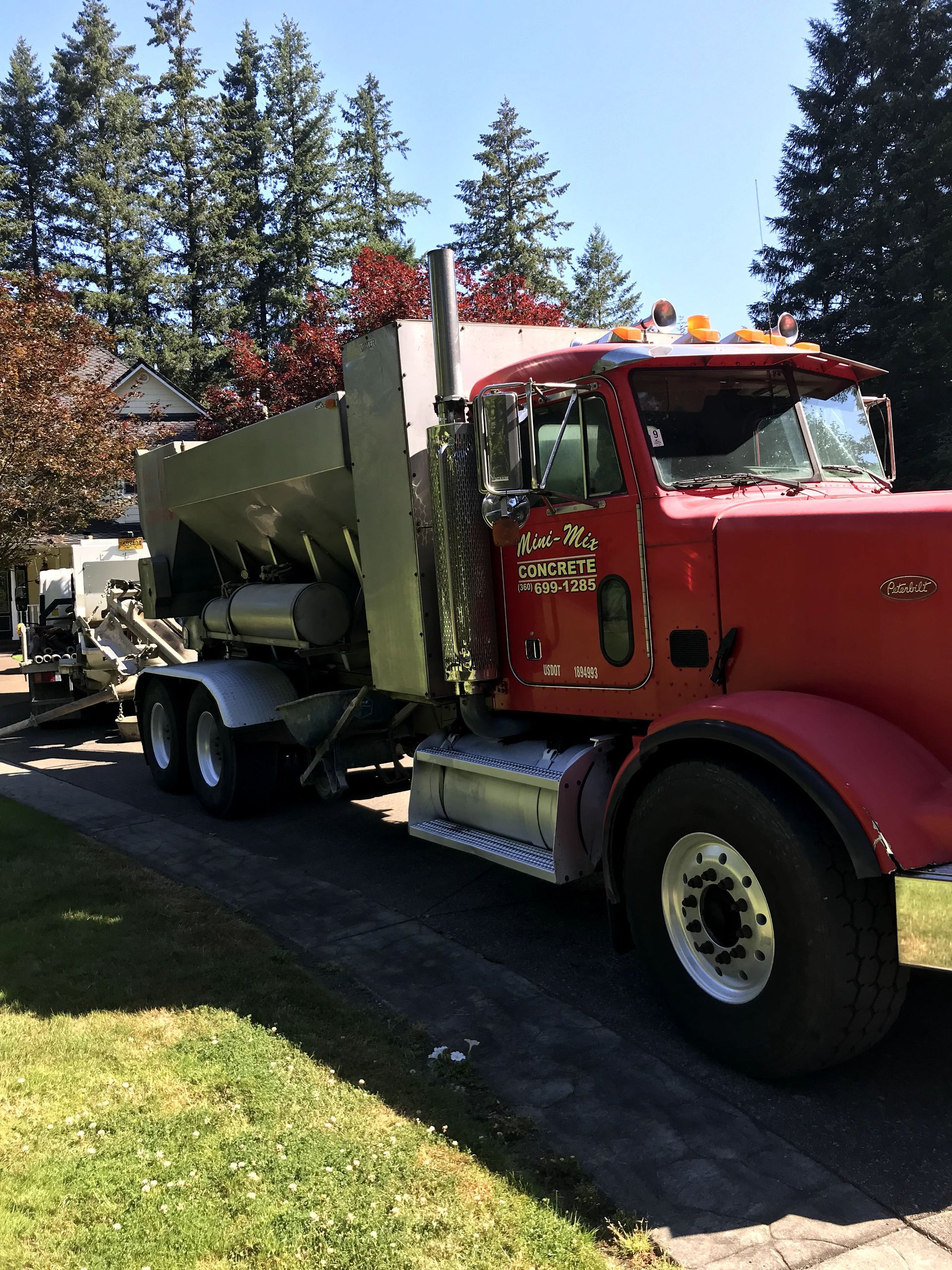 A red truck is parked in a driveway with trees in the background.