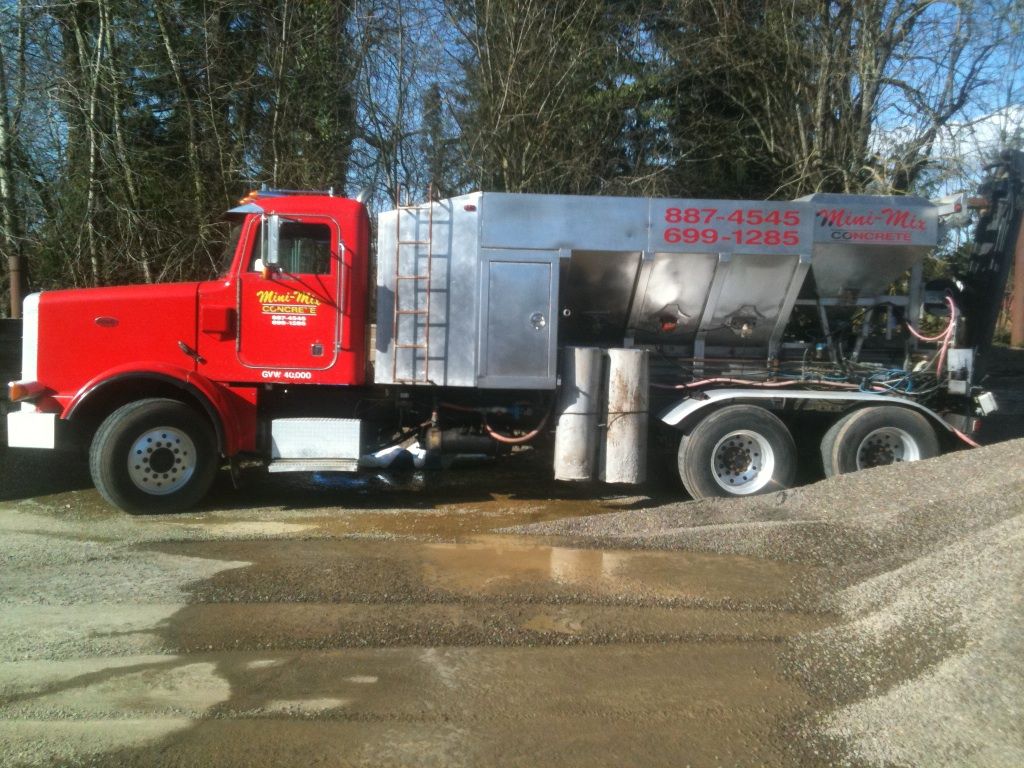 A red truck is parked in a gravel lot