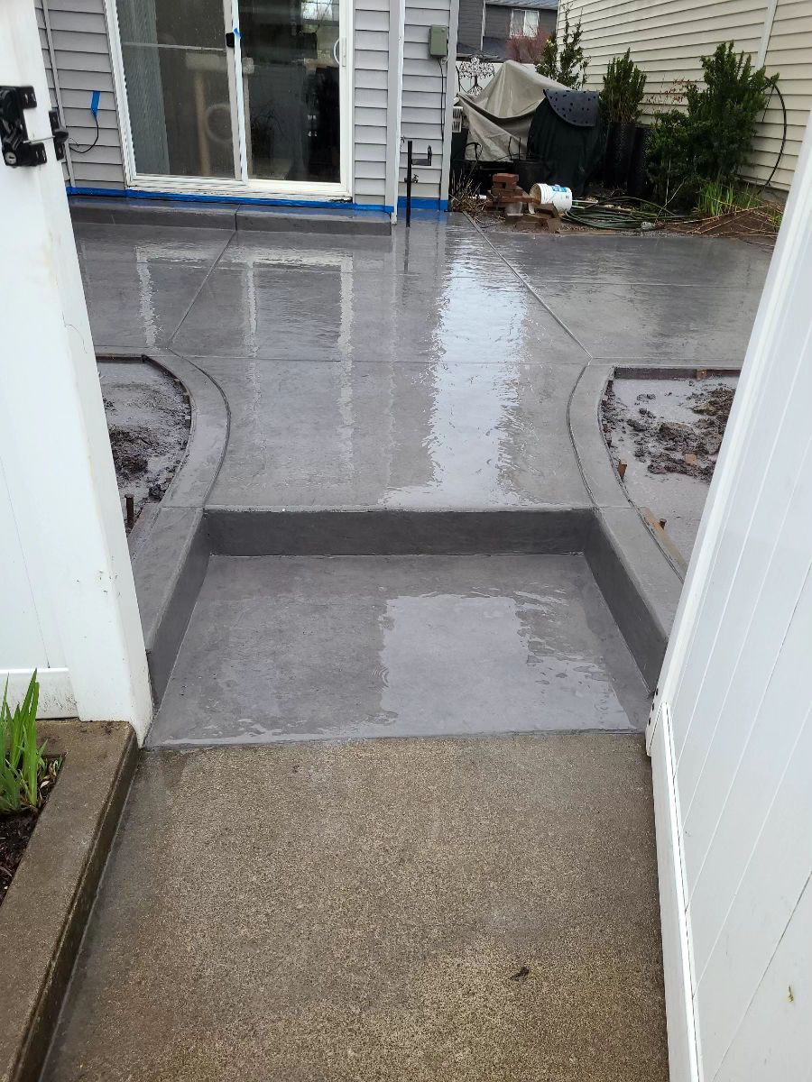 A concrete walkway leading to a patio with a sliding glass door.