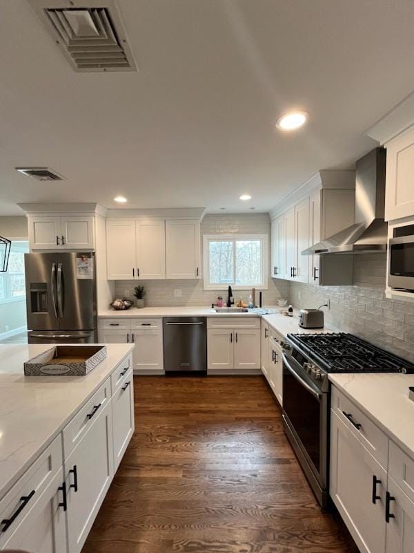 A modern kitchen featuring white cabinets, stainless steel appliances, white countertops, and hardwood flooring.