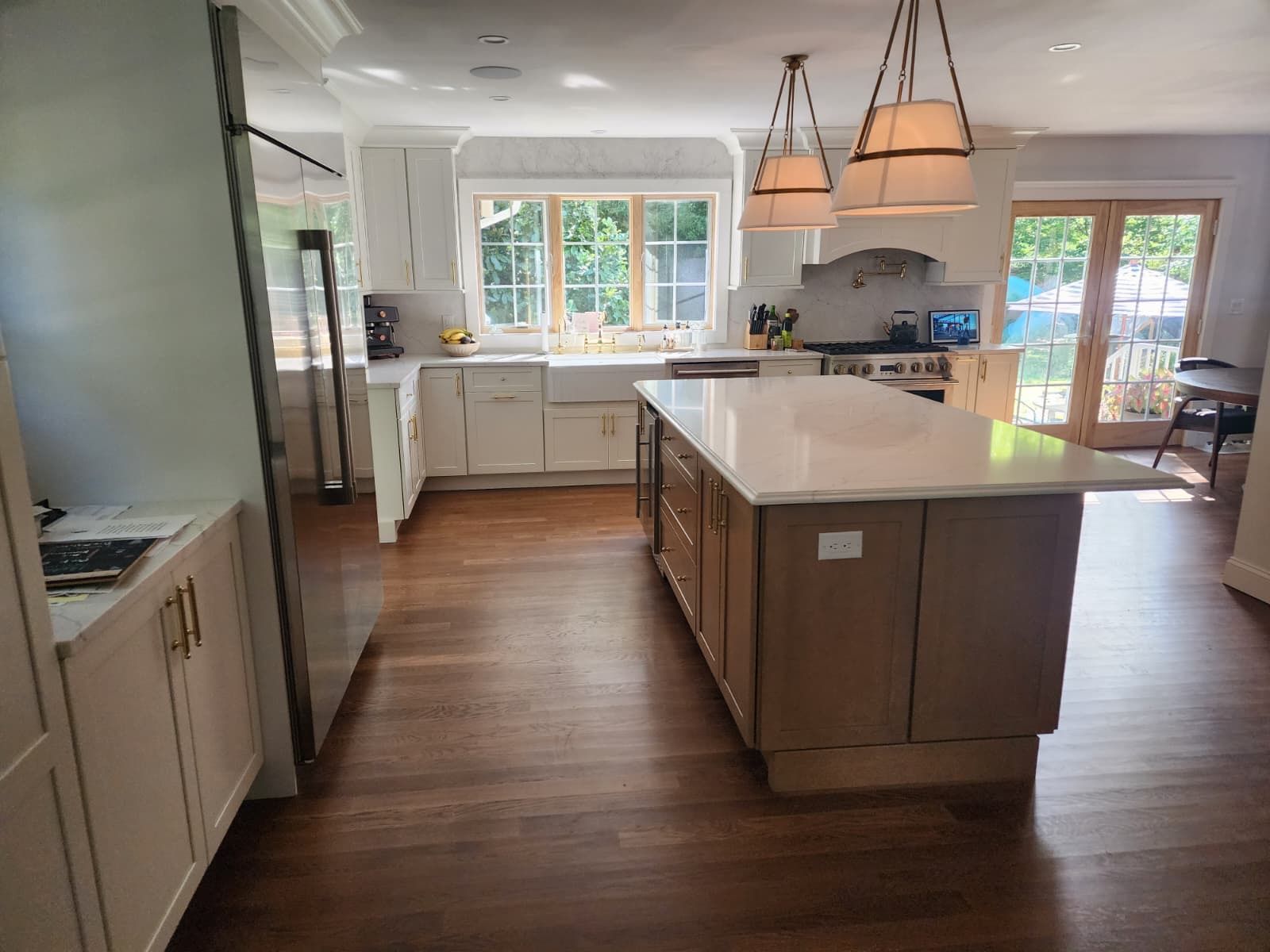 A well-lit, modern kitchen featuring white cabinetry, a large wooden island with a white countertop, and hardwood floors.