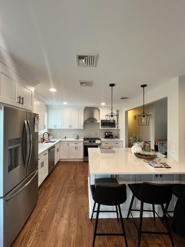 A bright, modern kitchen with white cabinets, stainless steel appliances, a white island with bar stools, and wood floors.