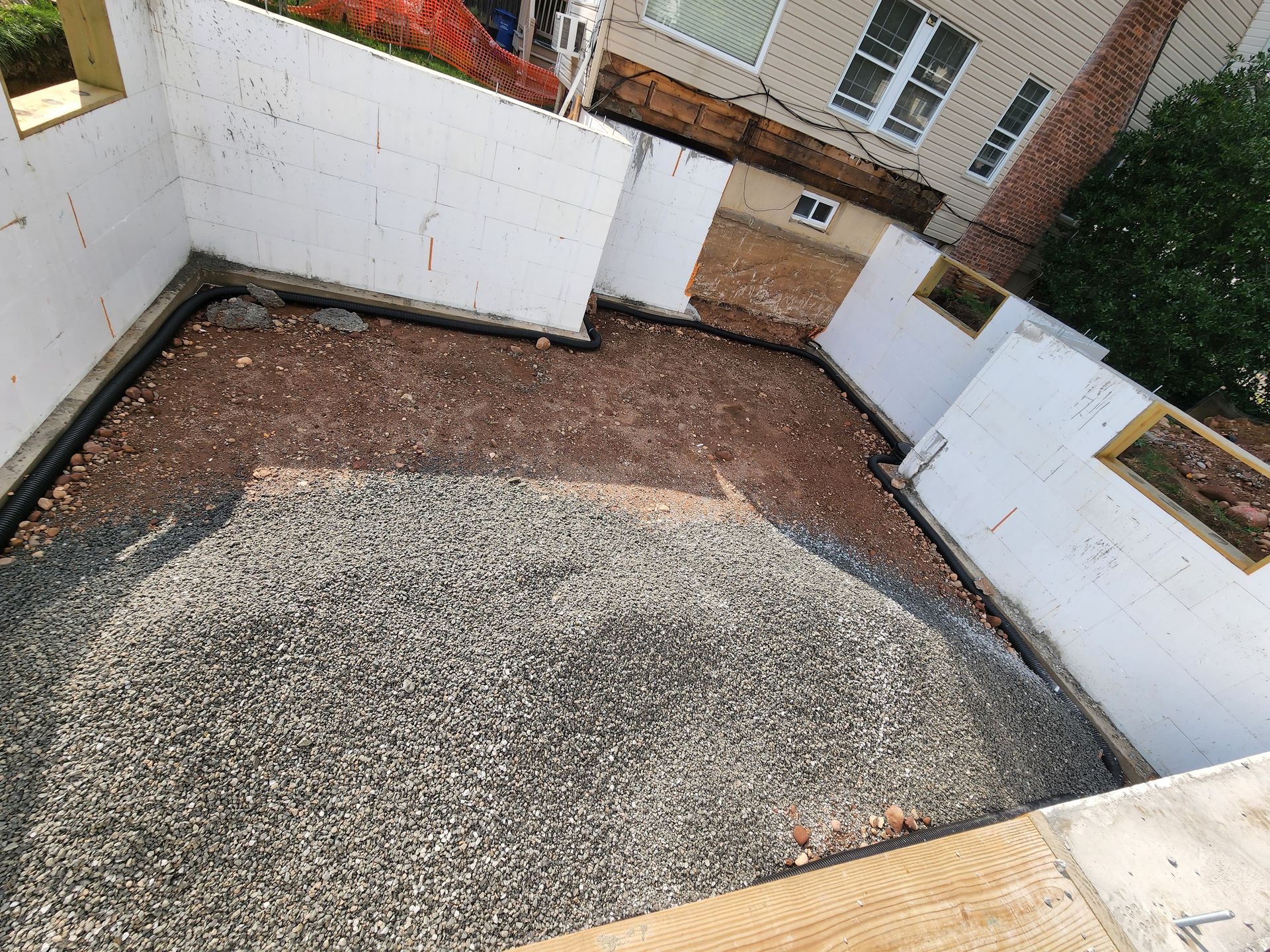 High-angle view of a construction site with white foam block walls surrounding a floor of gravel and dirt.