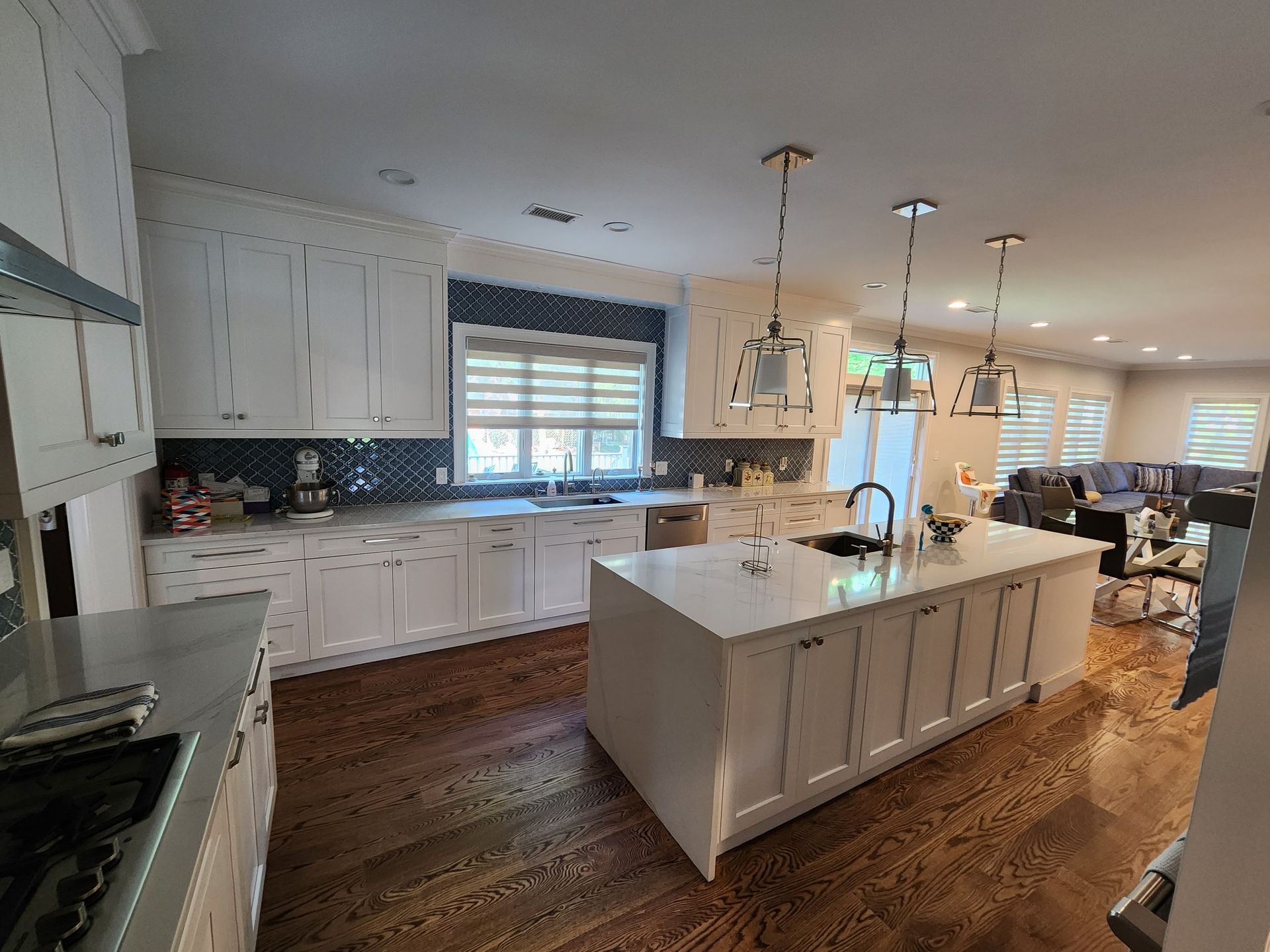 A bright, open-concept kitchen with white cabinetry, a large center island, and dark wood floors.