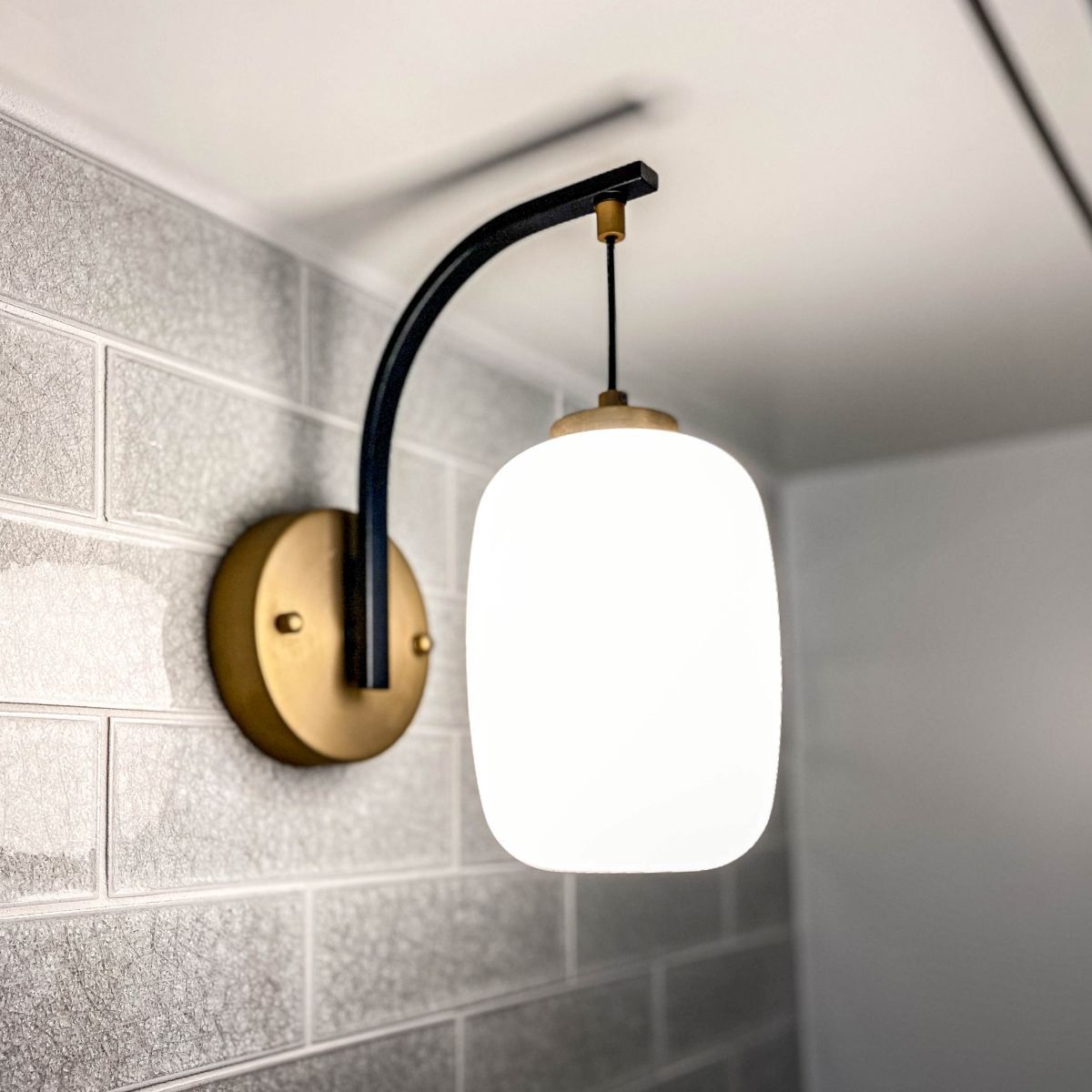 A wall mounted light with a white glass shade
