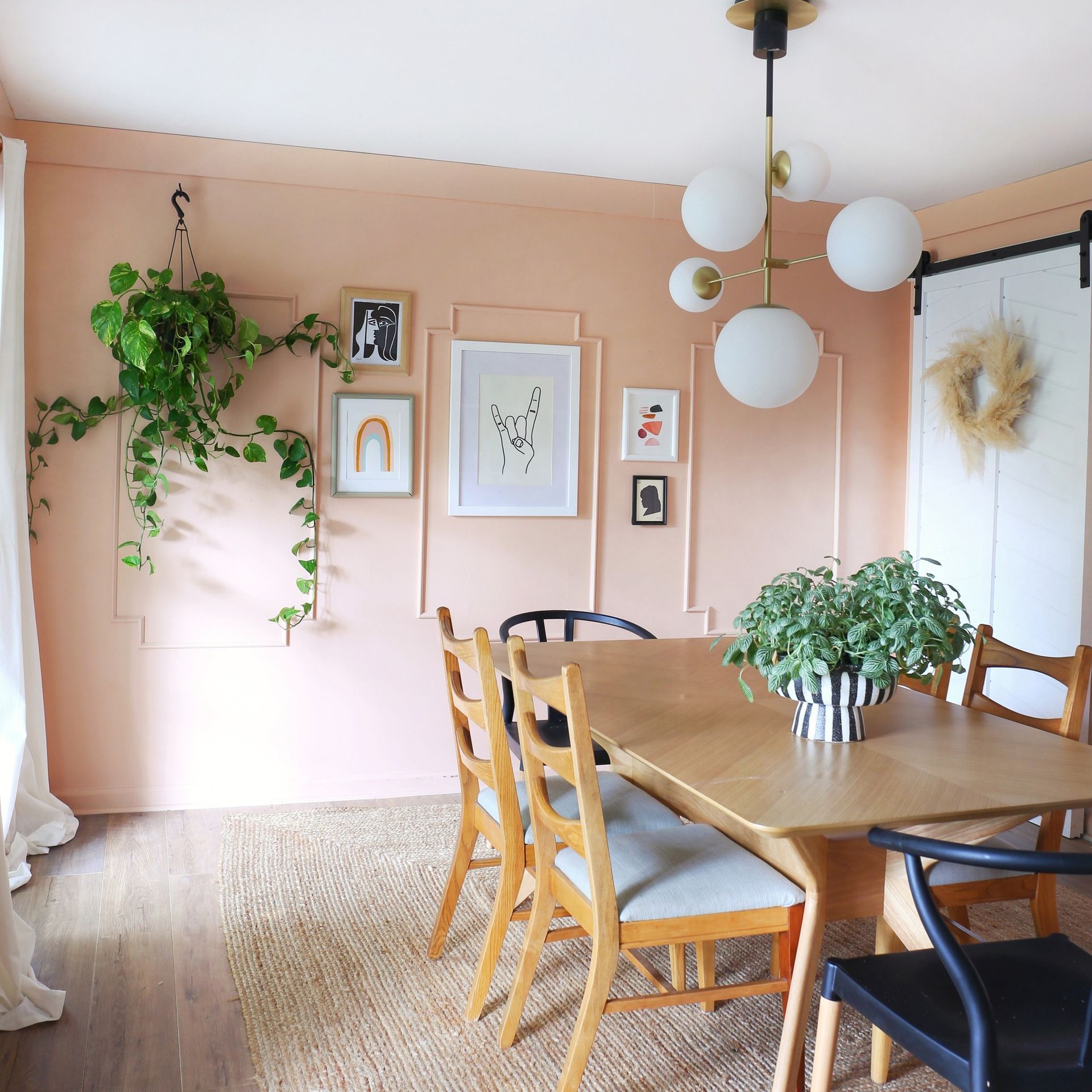 A dining room with a table and chairs and pink walls