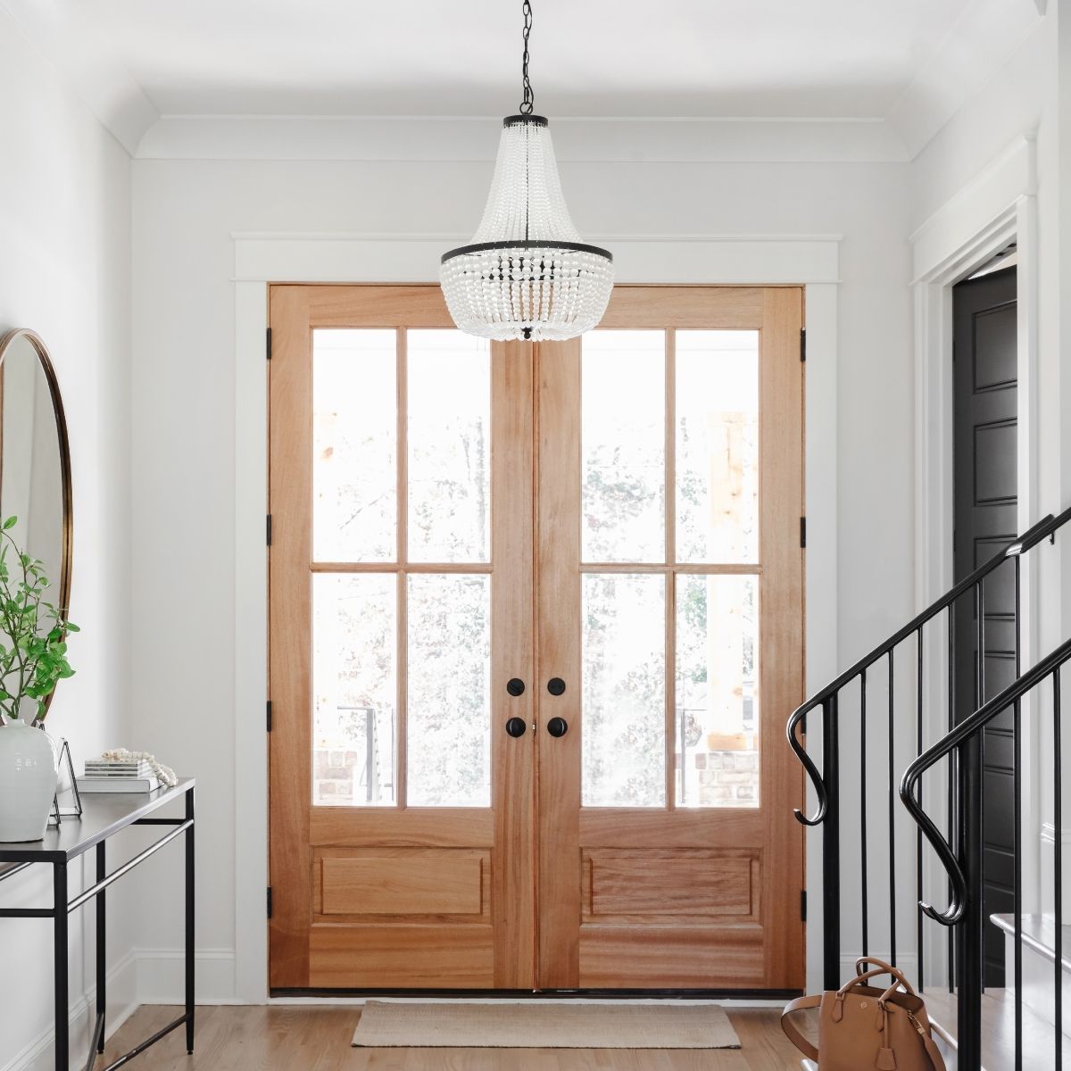 A hallway with a wooden door and a chandelier hanging from the ceiling.