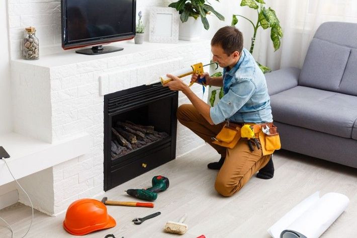 A man is installing a fireplace in a living room.