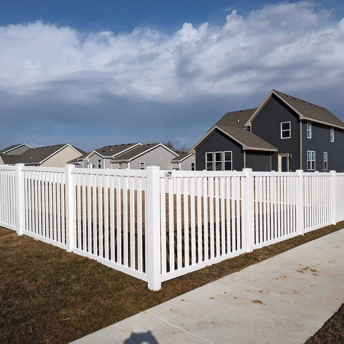 A white fence surrounds a house in a residential area