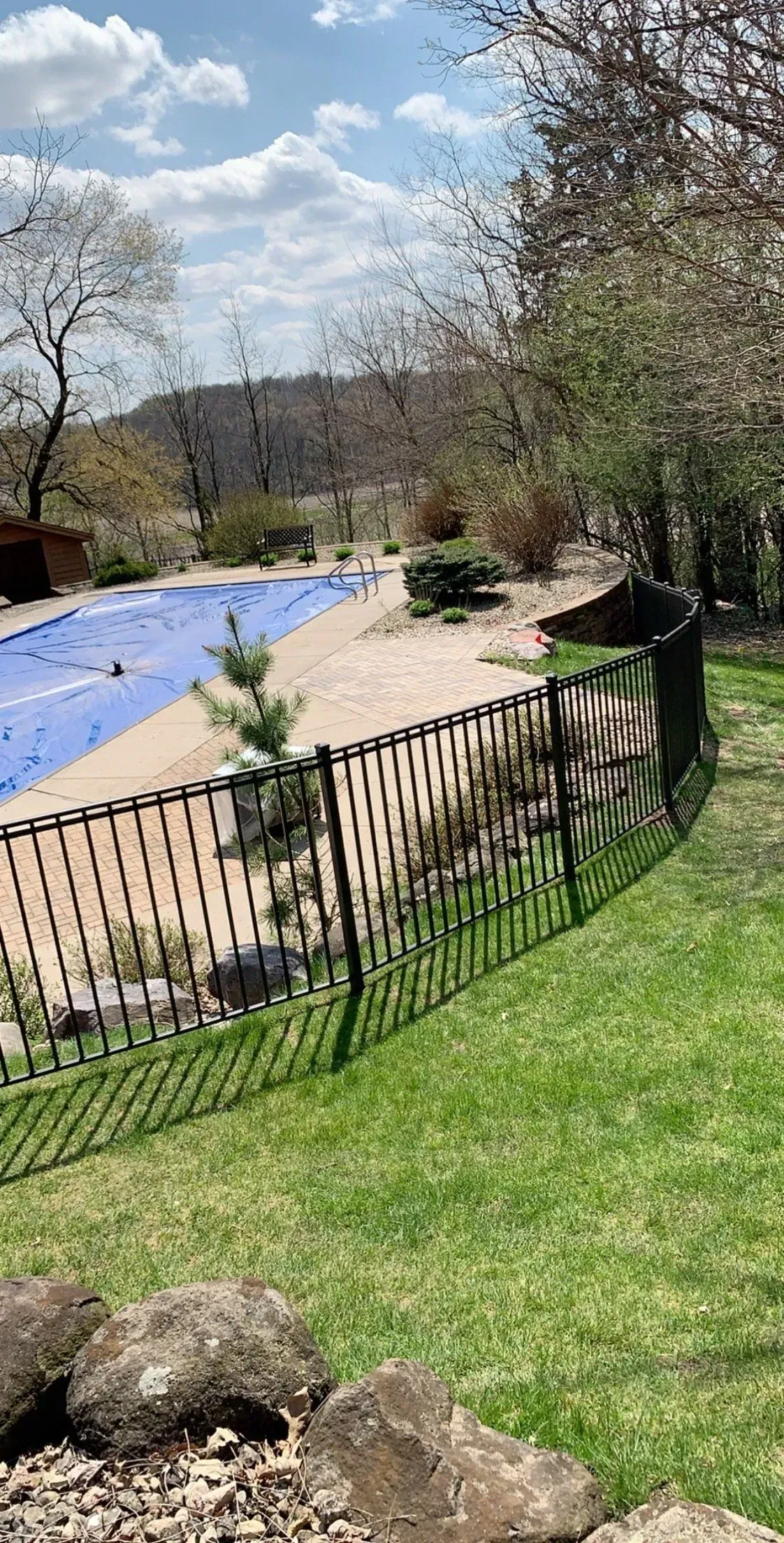 A fence surrounds a swimming pool in a backyard.