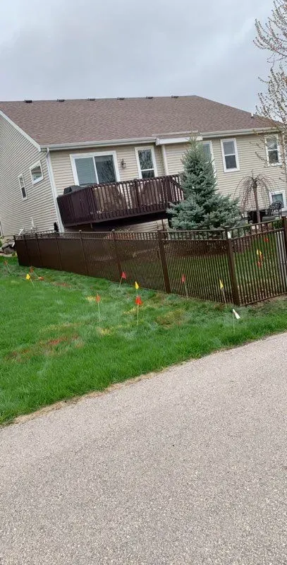 A house with a deck and a fence in front of it.