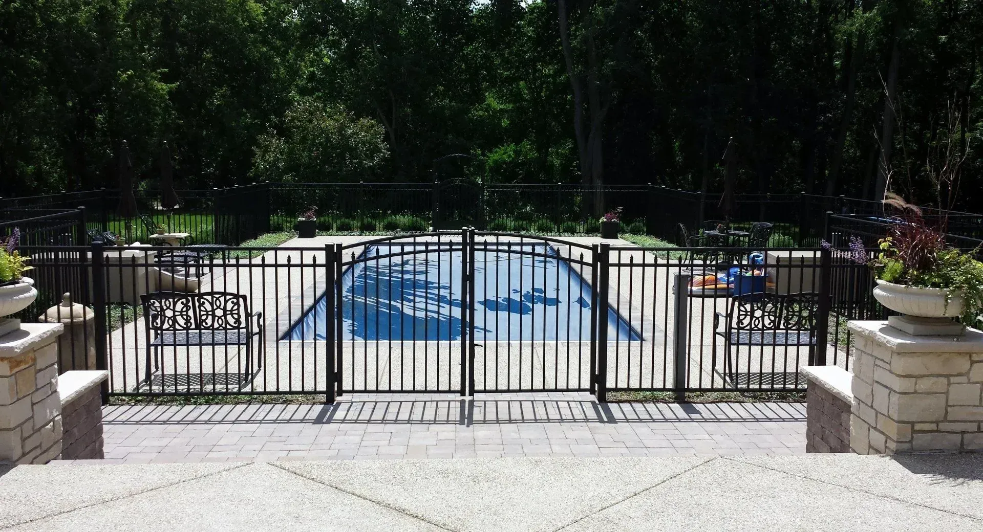 A black fence surrounds a large swimming pool