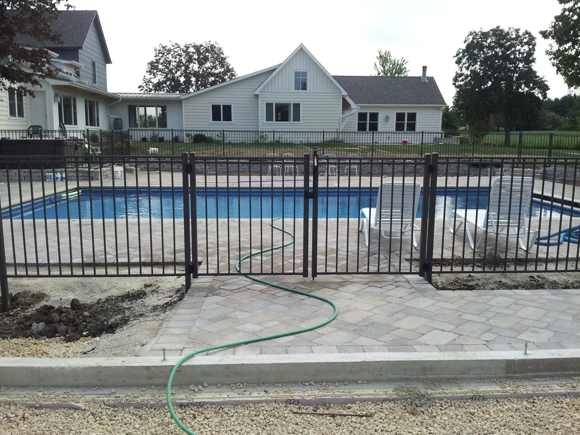 A fence around a swimming pool with a house in the background