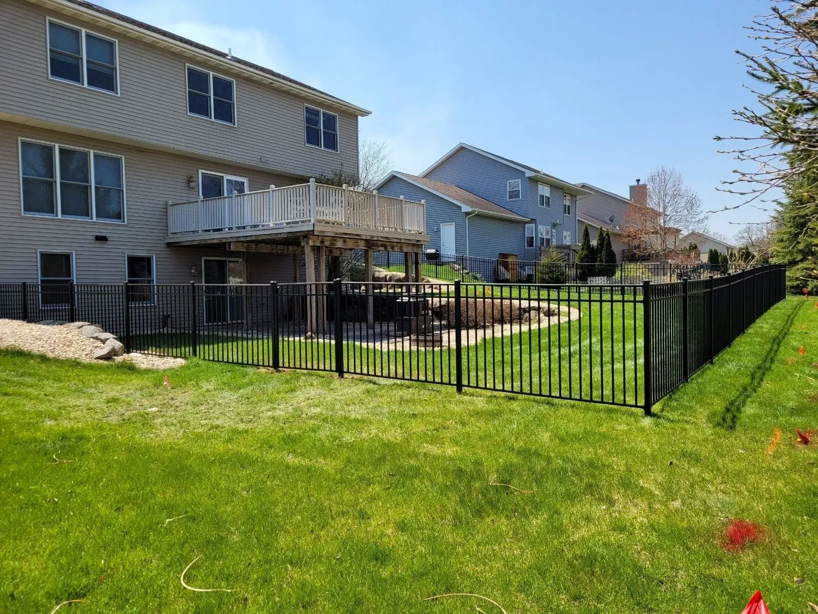 A backyard with a black fence and a house in the background.