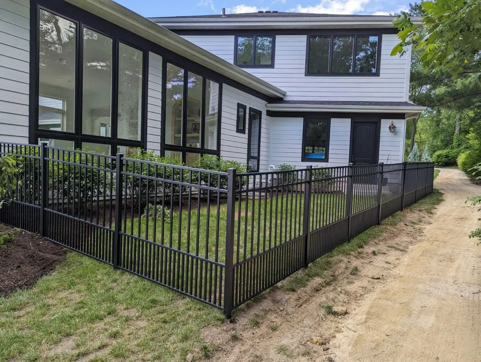 A white house with a black fence in front of it.