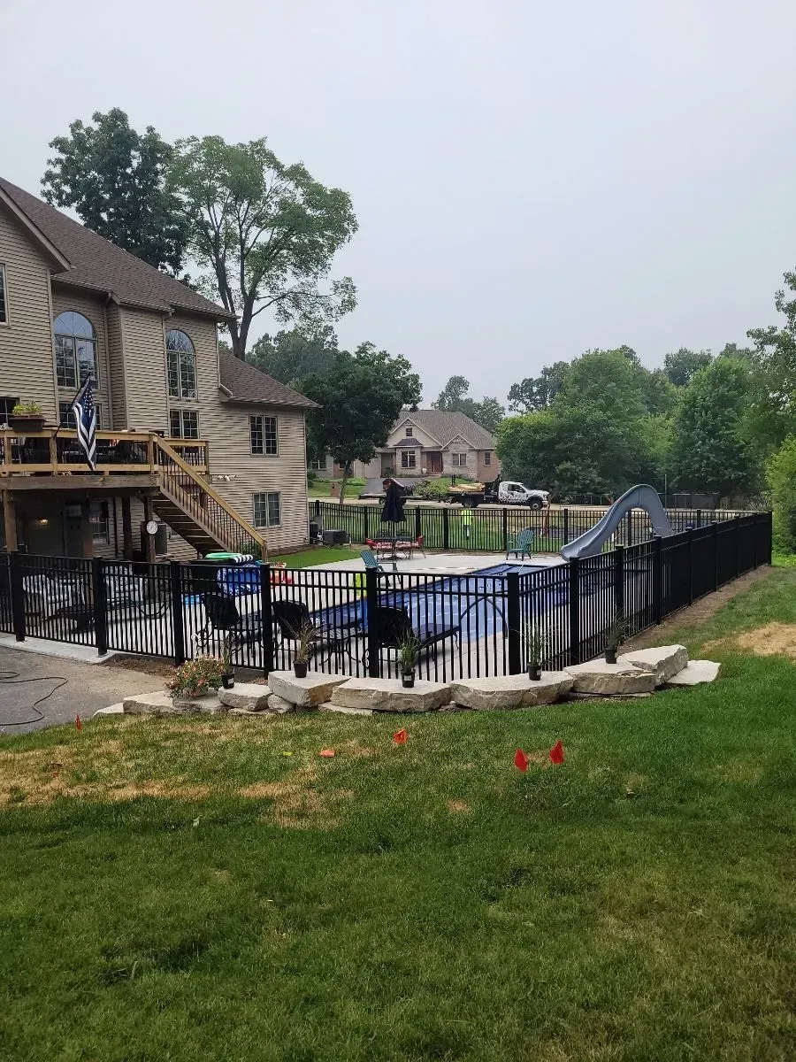A large house with a swimming pool behind a fence.