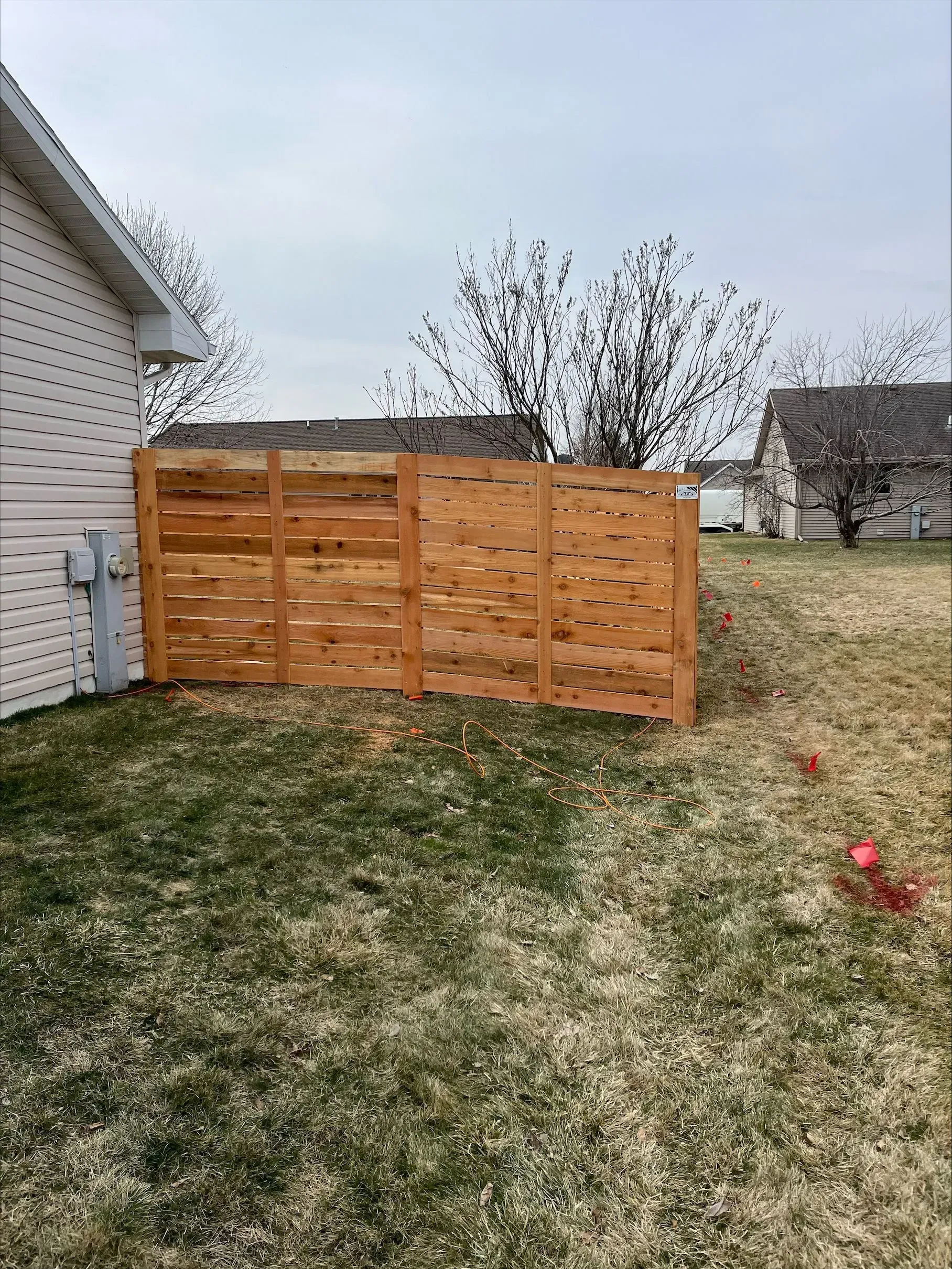 A wooden fence is in the backyard of a house.