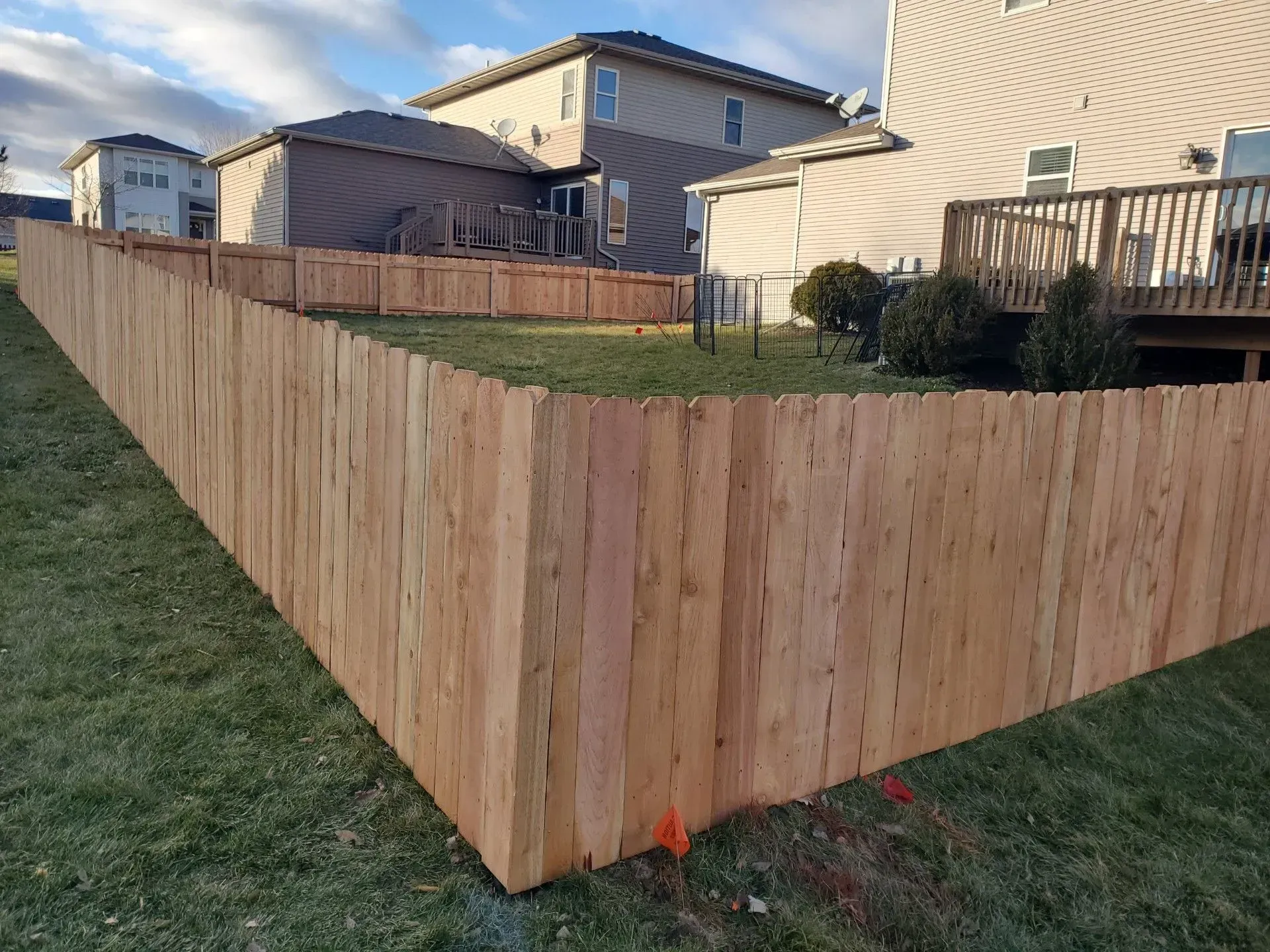 A wooden fence is in the backyard of a house.
