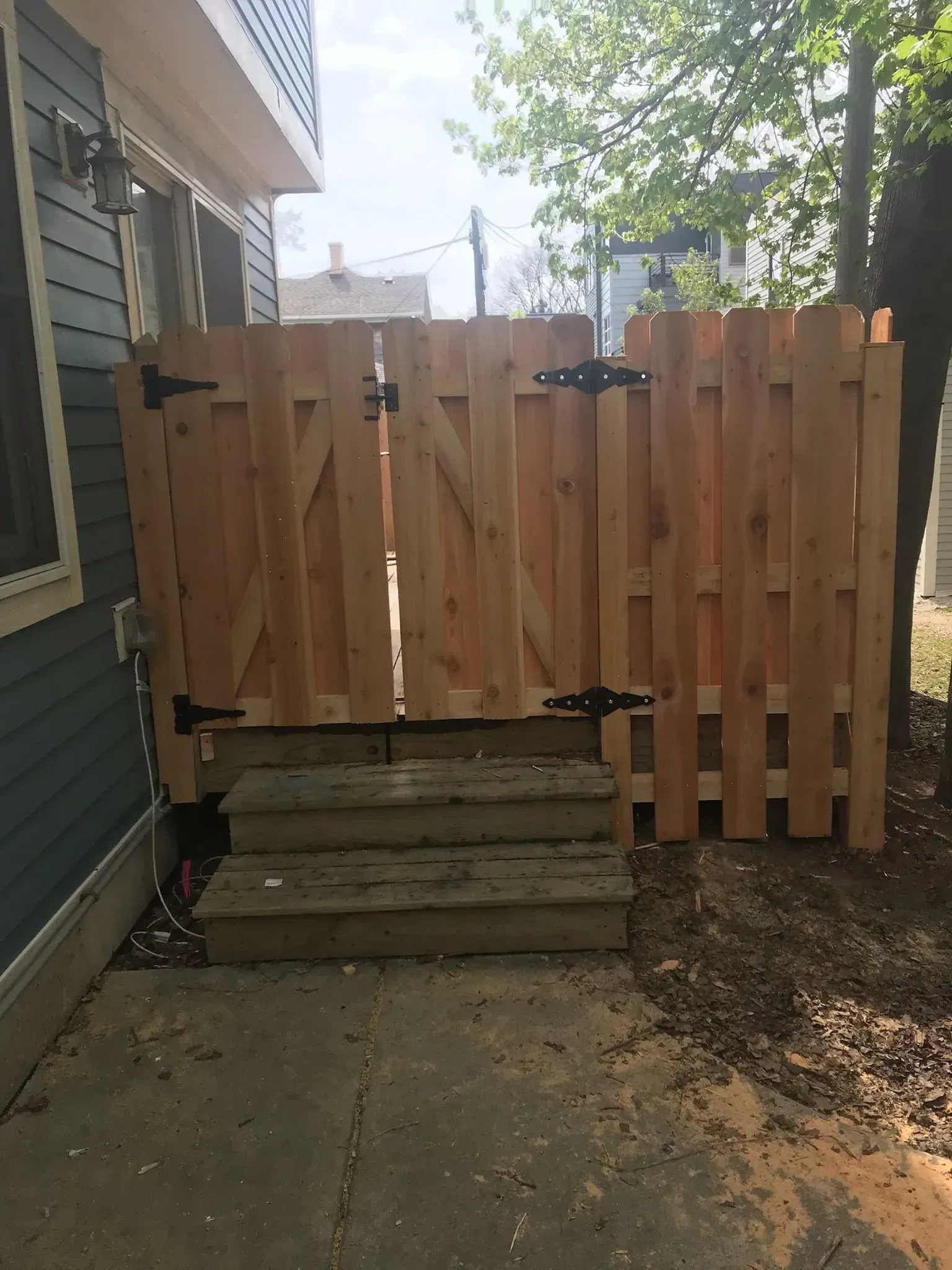A wooden fence with a gate is in front of a house.