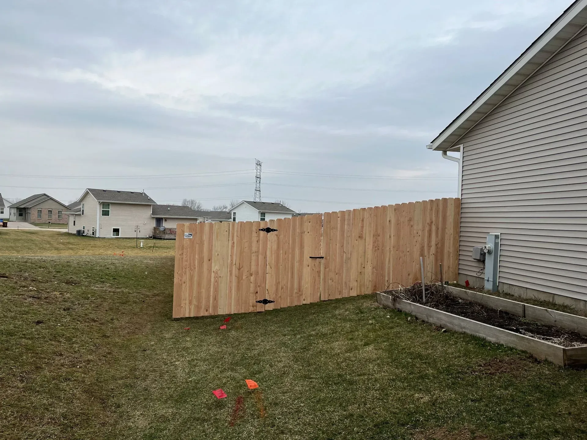 A wooden fence is in the backyard of a house.