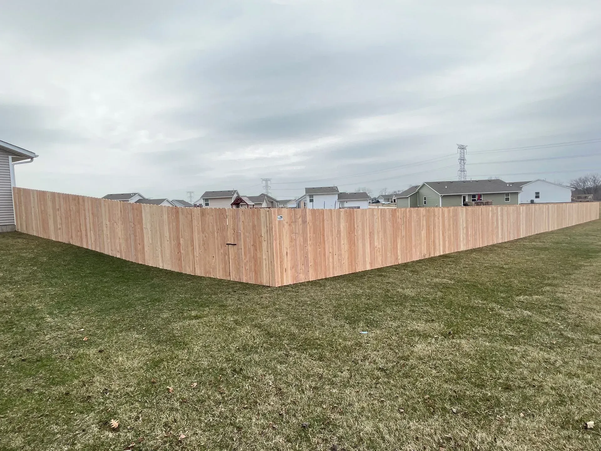 A wooden fence is in the middle of a grassy field.