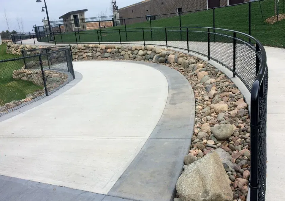 A concrete walkway with a chain link fence surrounding it