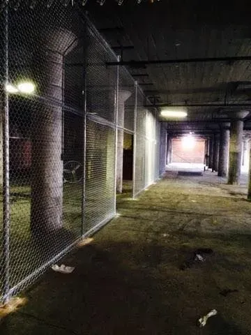 An empty parking garage with a chain link fence surrounding it at night.