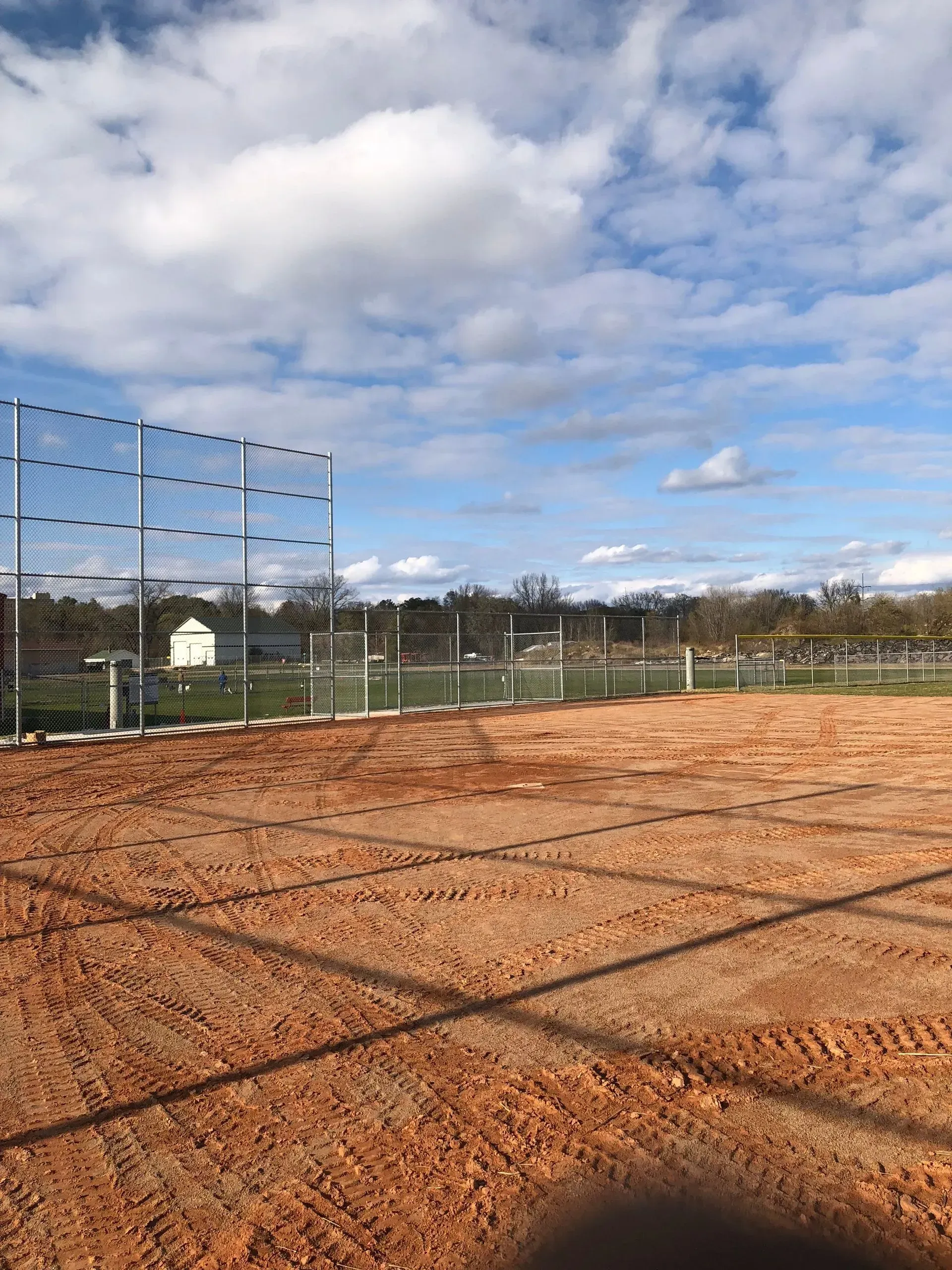 A baseball field with a fence and a blue sky in the background.