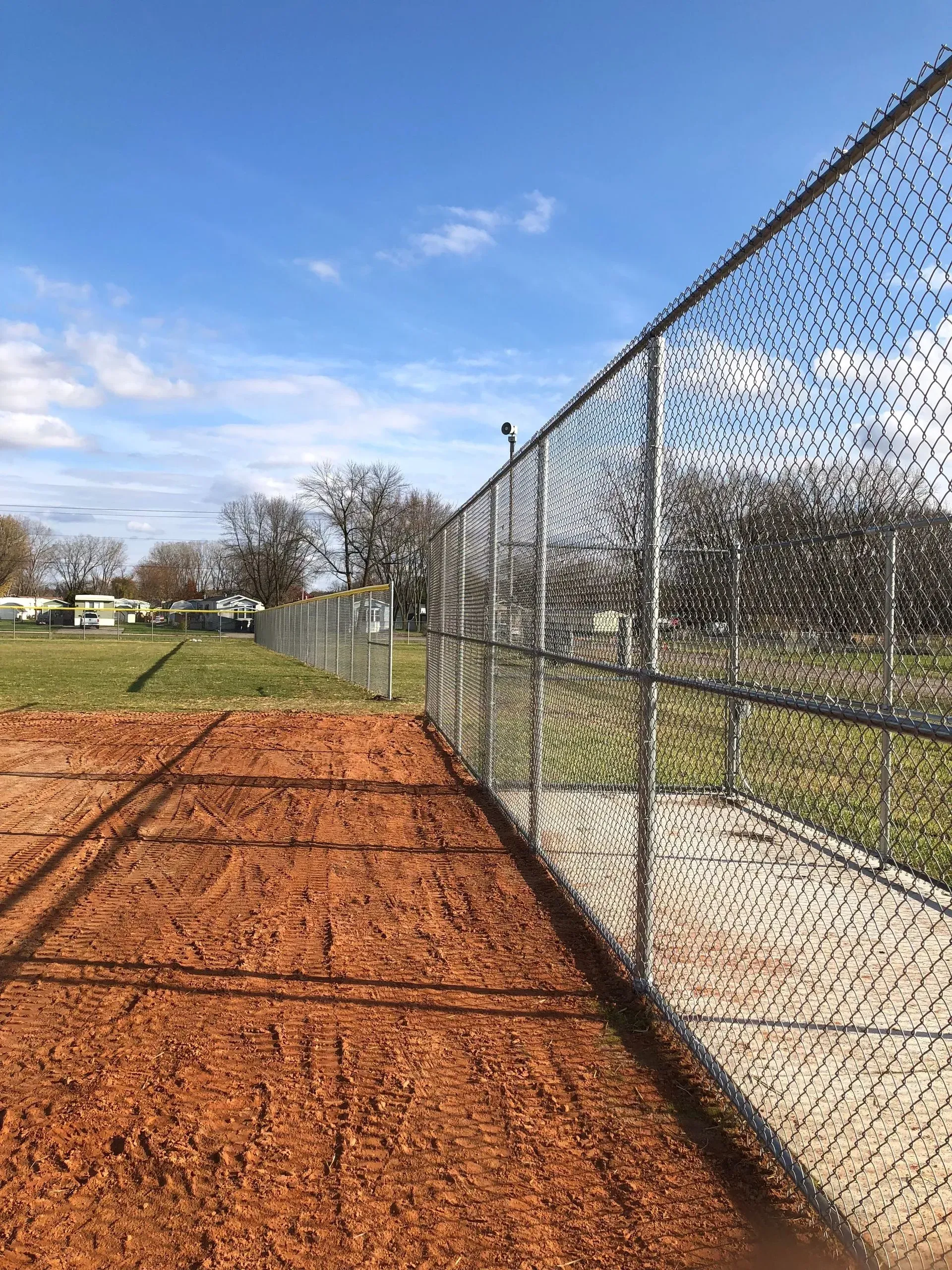 A chain link fence surrounds a baseball field.