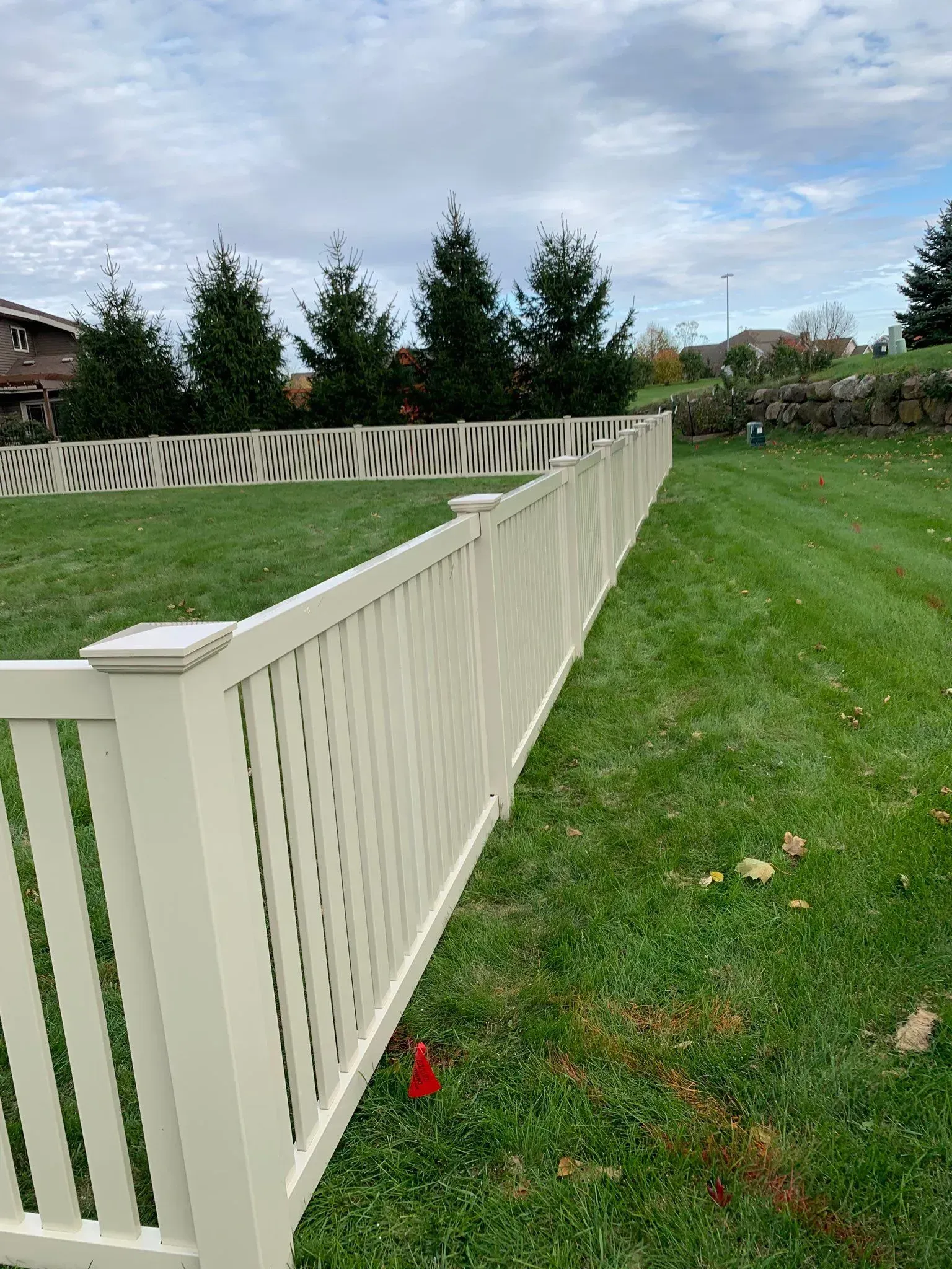 A white fence is sitting in the middle of a lush green field.