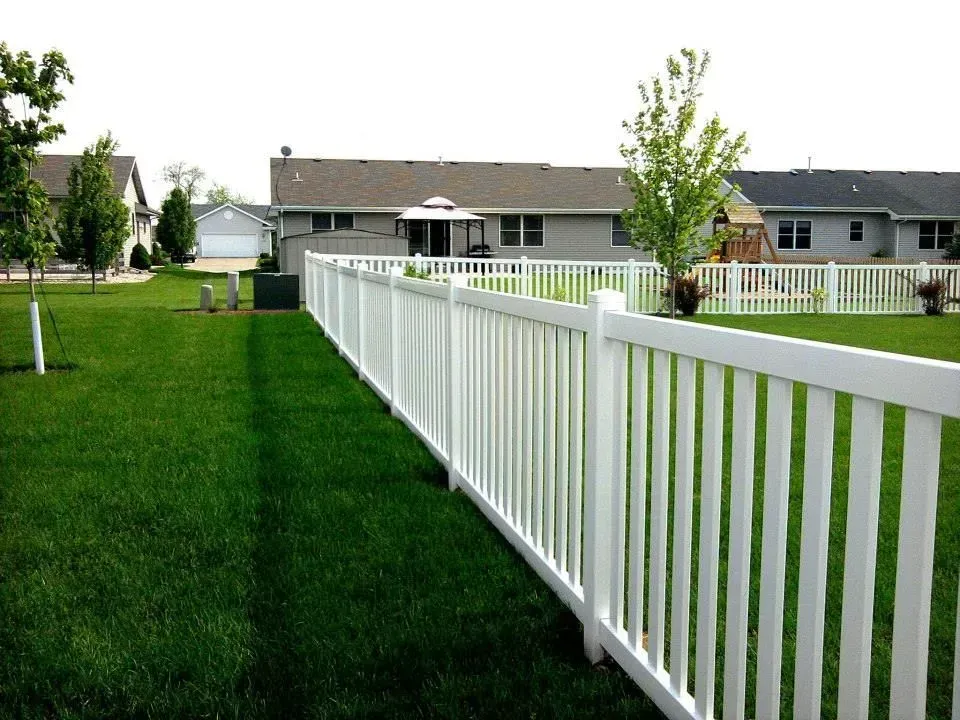 A white fence surrounds a lush green yard